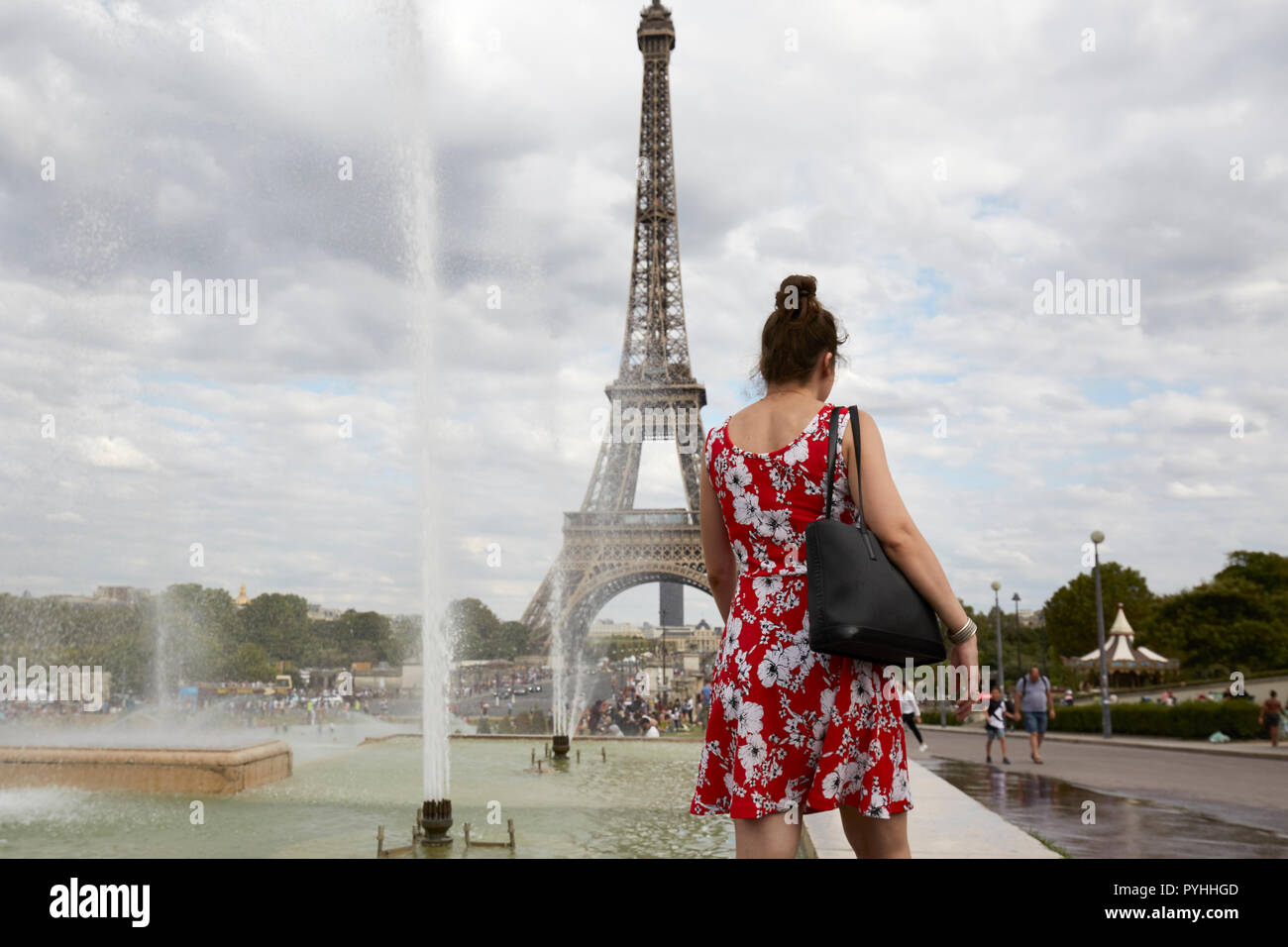 Paris, Ile-de-France, France - une femme avec une robe rouge et blanche à la fontaine dans les Jardins du Trocadéro avec la Tour Eiffel en arrière-plan. Banque D'Images