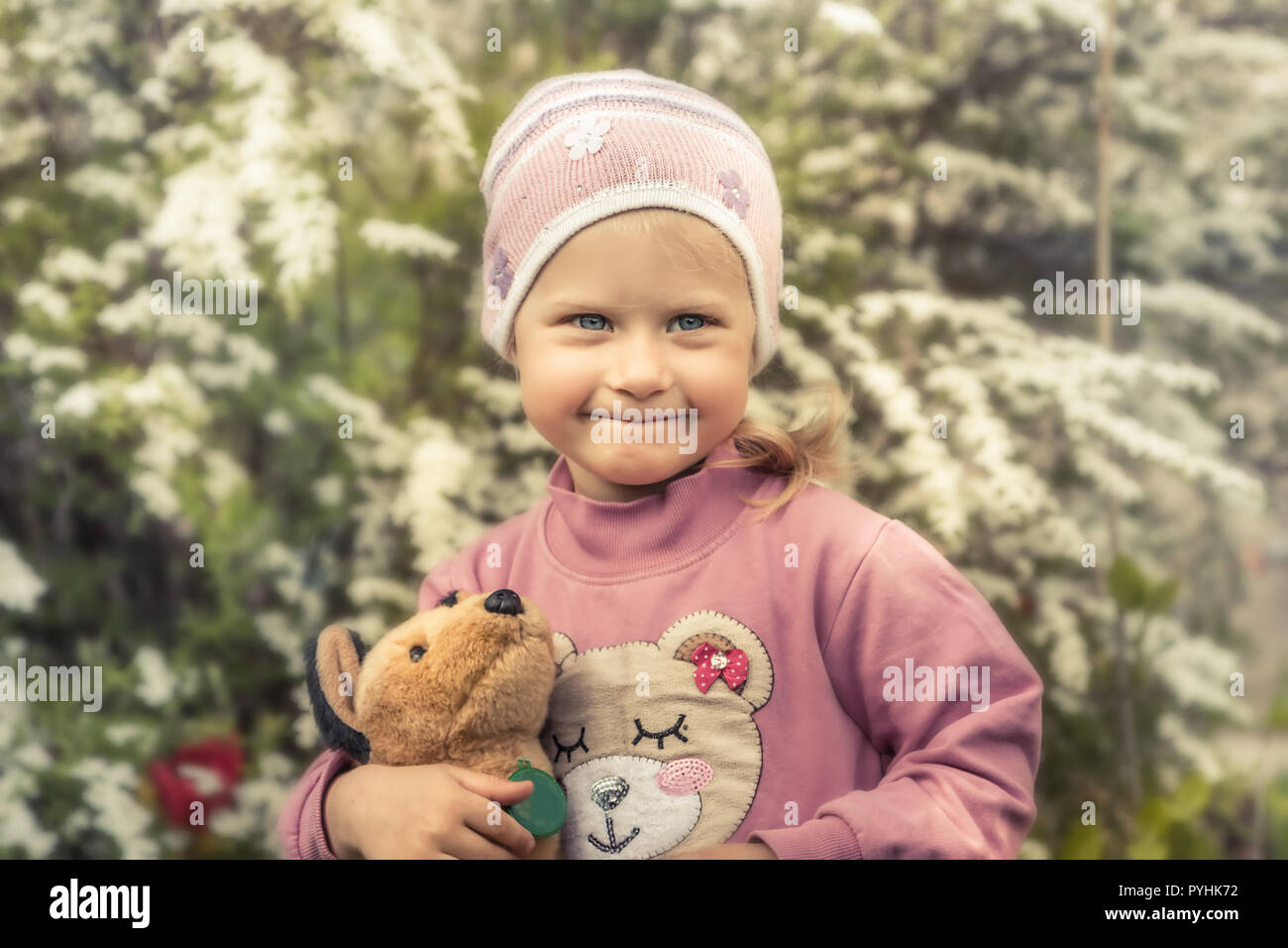 Enfant mignon timide fille avec toy smiling portrait soft flowers background concept enfance heureuse vie Banque D'Images