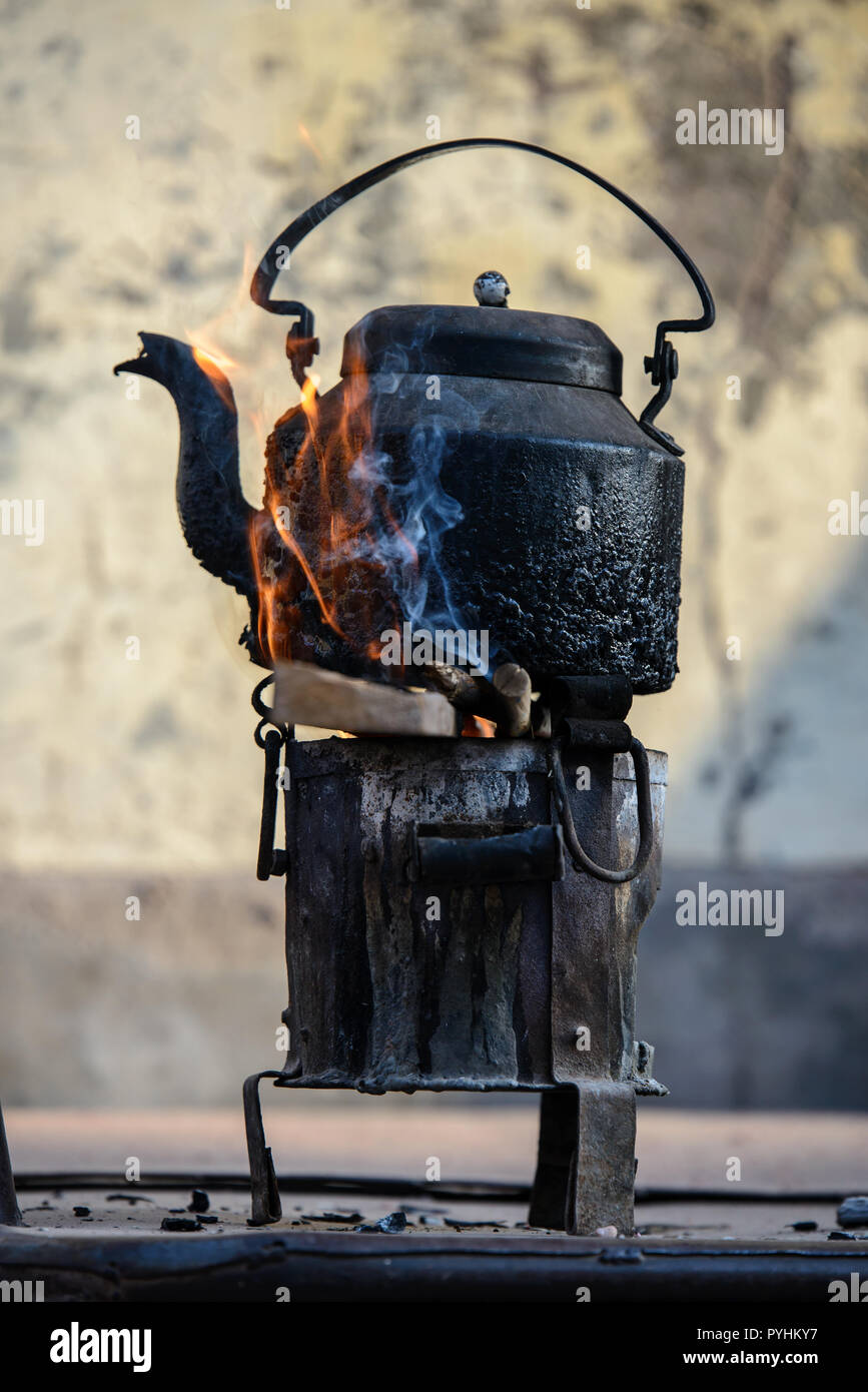 Vieux métal tea pot en flammes un incendie cuisinière Banque D'Images