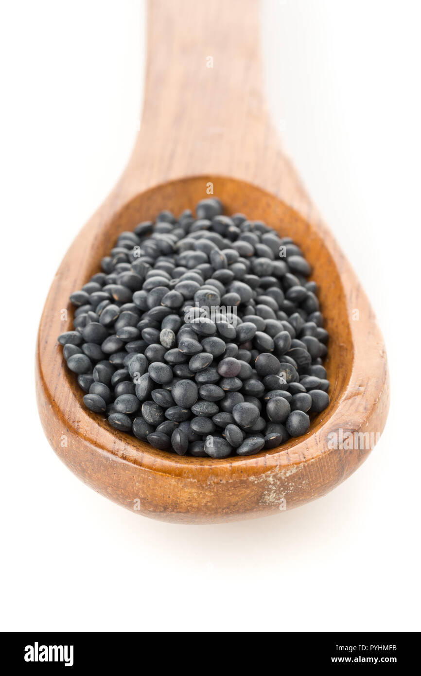 Tas de lentilles beluga bio noir en cuillère en bois sur fond blanc Banque D'Images