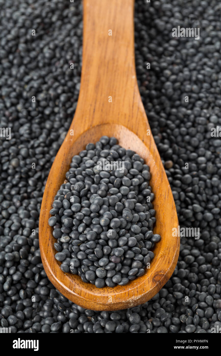 Tas de lentilles beluga bio noir en cuillère en bois noir sur fond de lentilles béluga Banque D'Images