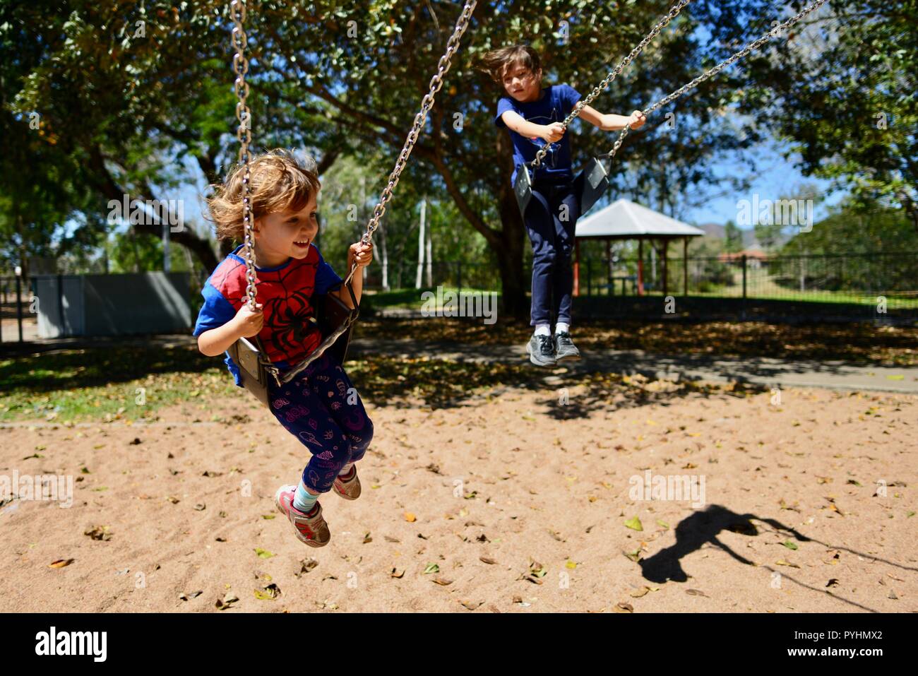 Un jeune enfant joue sur une balançoire dans un spiderman top, Ross River area, Townsville, Queensland, Australie Banque D'Images