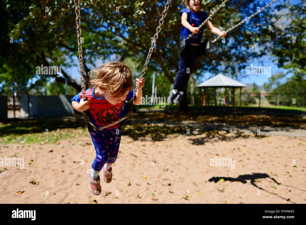 Un jeune enfant joue sur une balançoire dans un spiderman top, Ross River area, Townsville, Queensland, Australie Banque D'Images