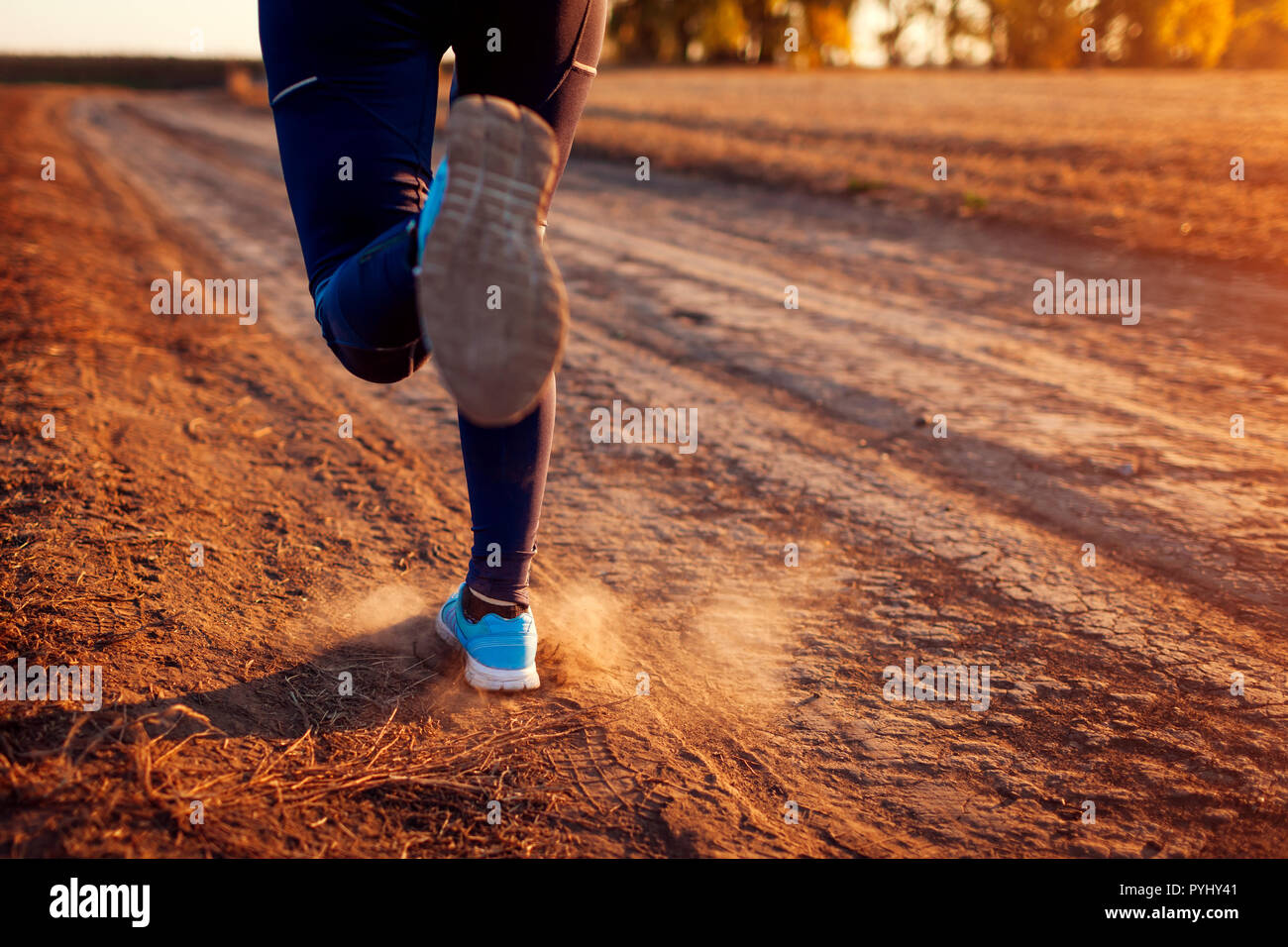 Femme d'exécution dans le champ d'automne au coucher du soleil. Concept de vie sain. Sportifs actifs. Close up de jambes Banque D'Images