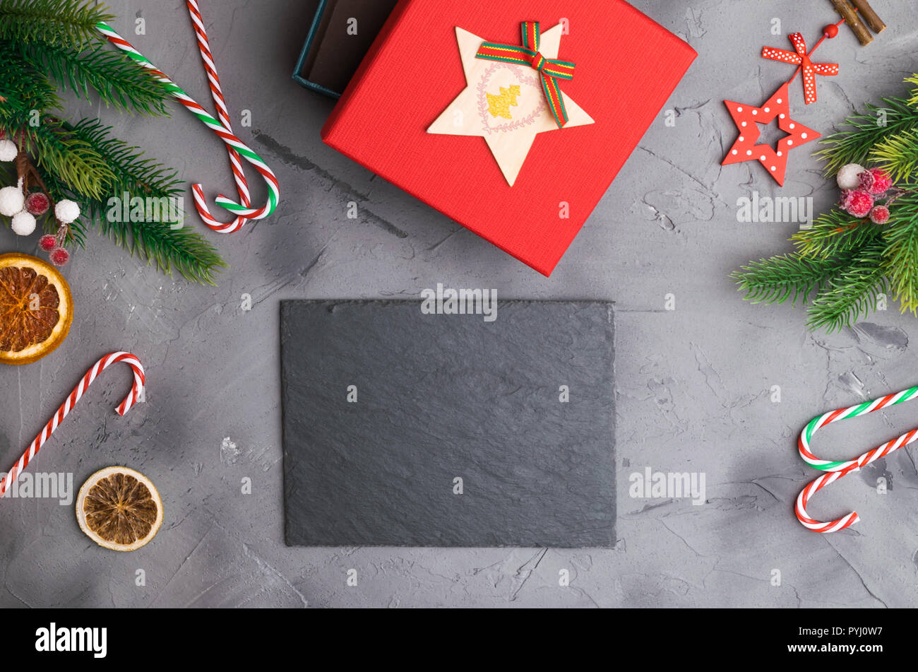 Branches de sapin sur fond gris béton avec boîte cadeau rouge. L'espace pour poser à plat du texte. Banque D'Images