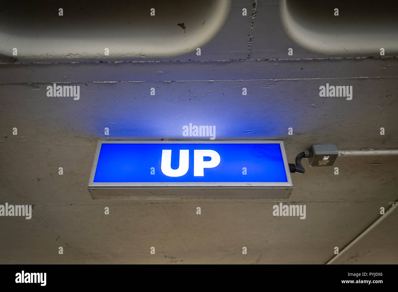 Bleu, éclairé 'UP' signer dans un parking Banque D'Images