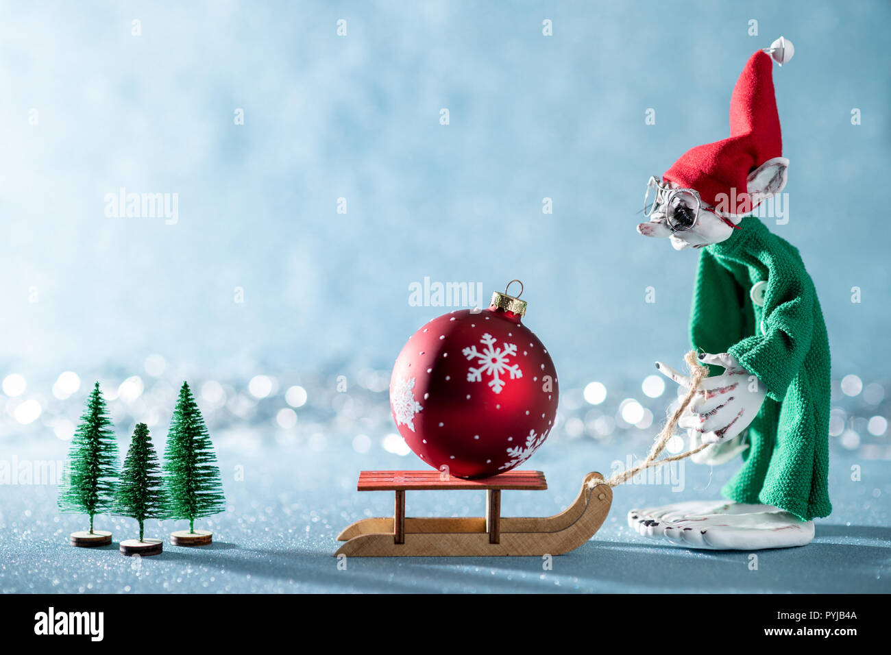 Cute Cheerful Santas Helper tirant un traîneau Santas Elf avec boule de noël.Scène de Noël au pôle Nord. Santas Atelier. Elf au travail. Banque D'Images