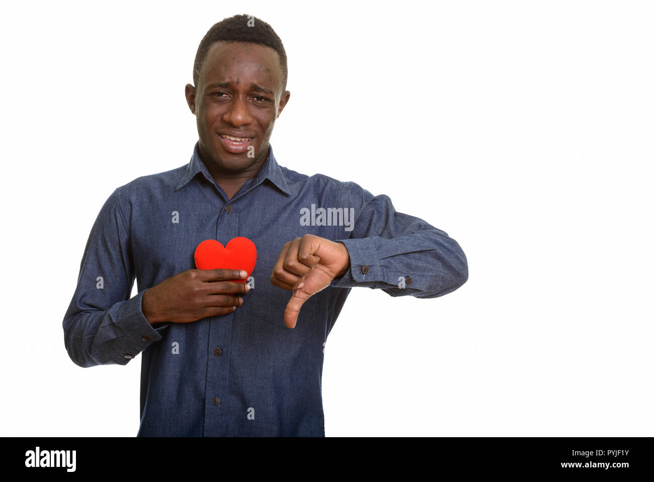 Sad Young African man holding cœur rouge sur la poitrine et donner thum Banque D'Images