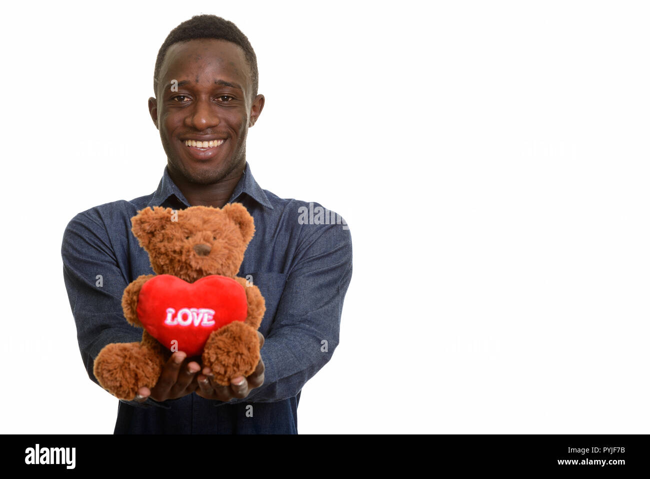 Les jeunes professionnels African man smiling et donner ours en peluche avec coeur Banque D'Images