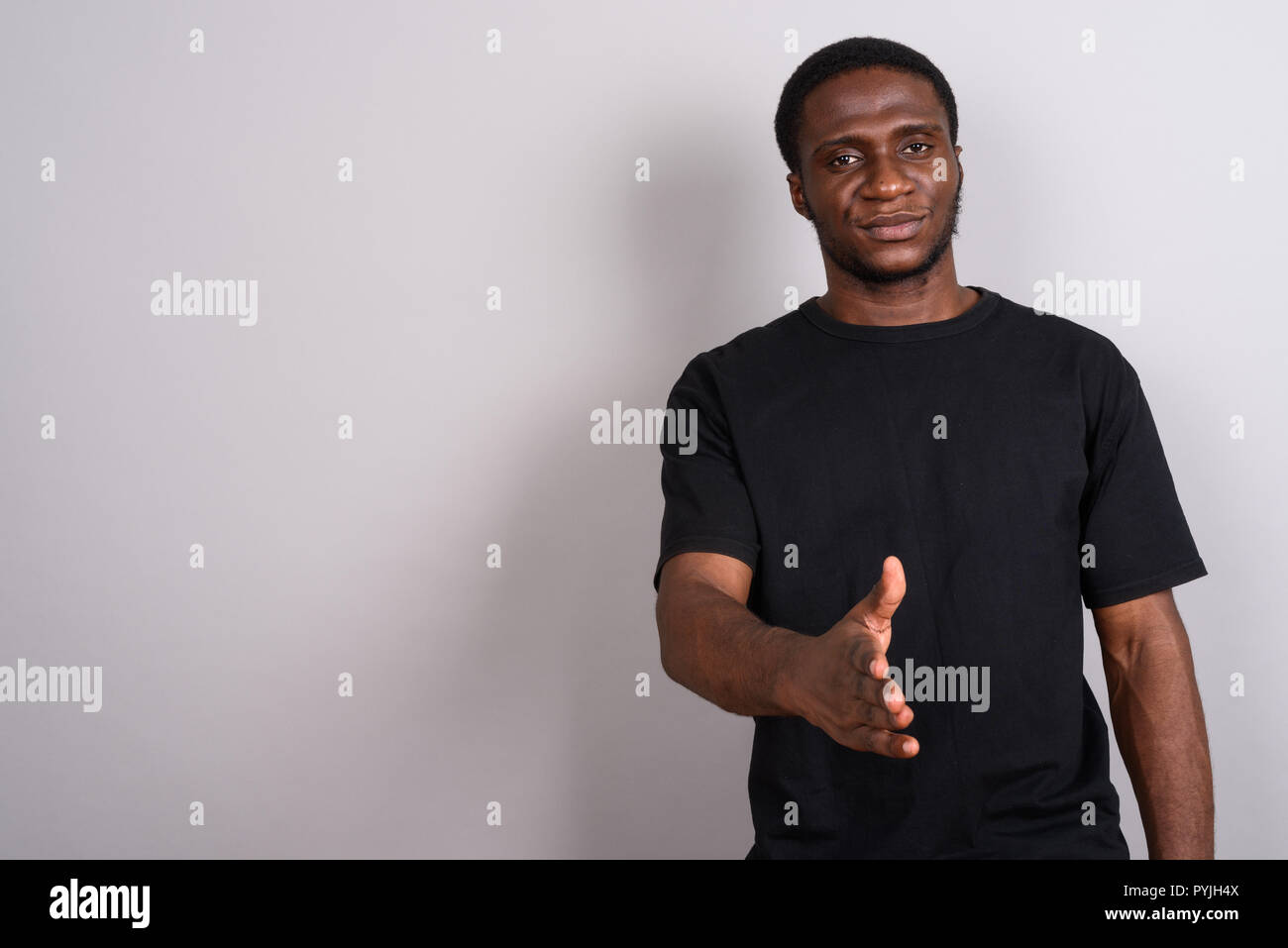 Jeune homme africain portant chemise noire contre l'arrière-plan gris Banque D'Images