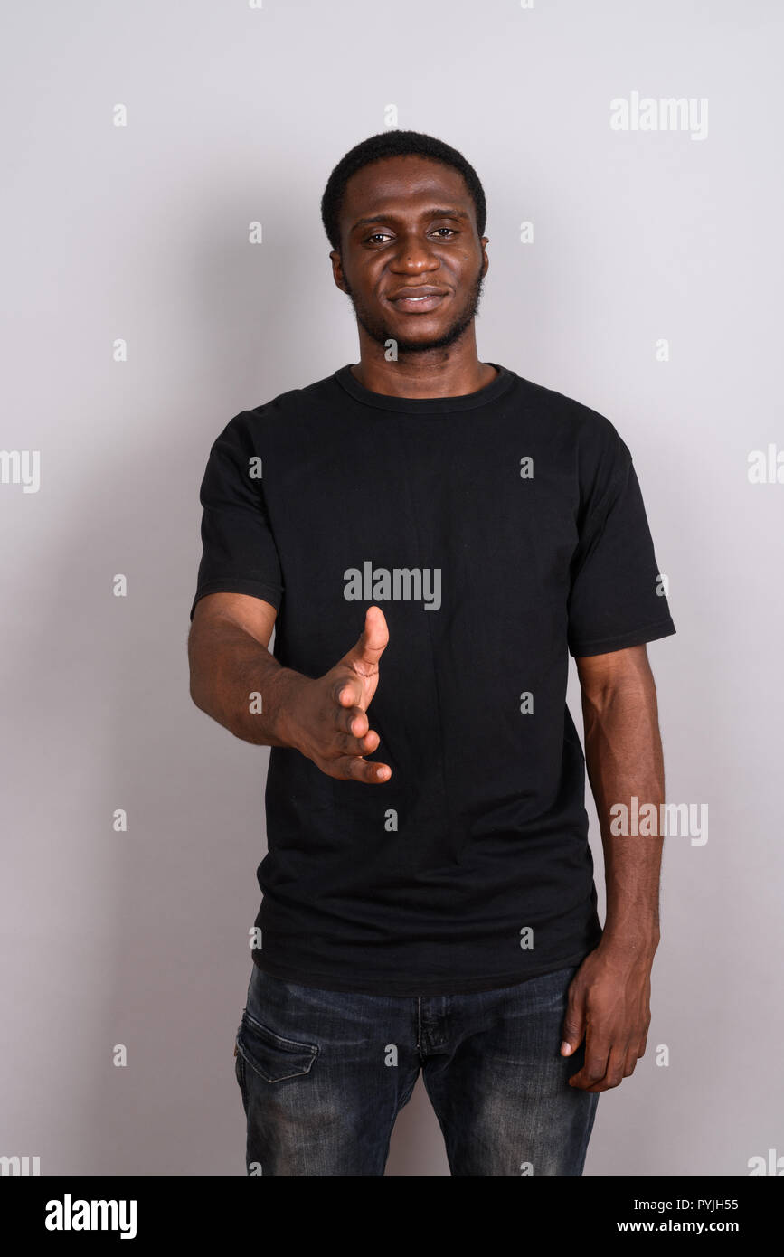 Jeune homme africain portant chemise noire contre l'arrière-plan gris Banque D'Images
