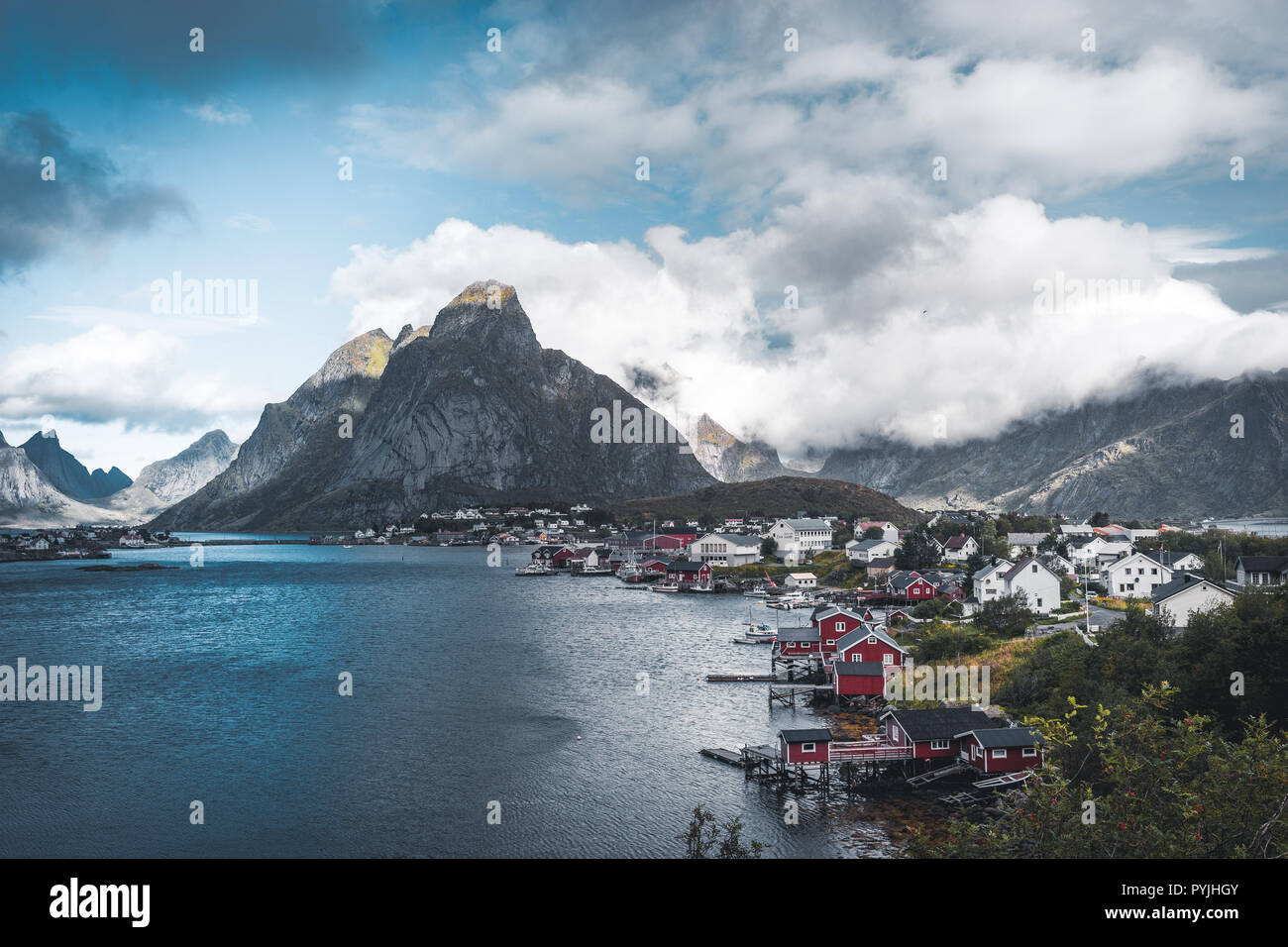 Paysage du village de pêche Reine avec la Reine Fjord pendant le coucher du soleil avec de belles lumières sur montagne, ciel bleu et nuages. Lofoten, Norvège. Photo prise Banque D'Images