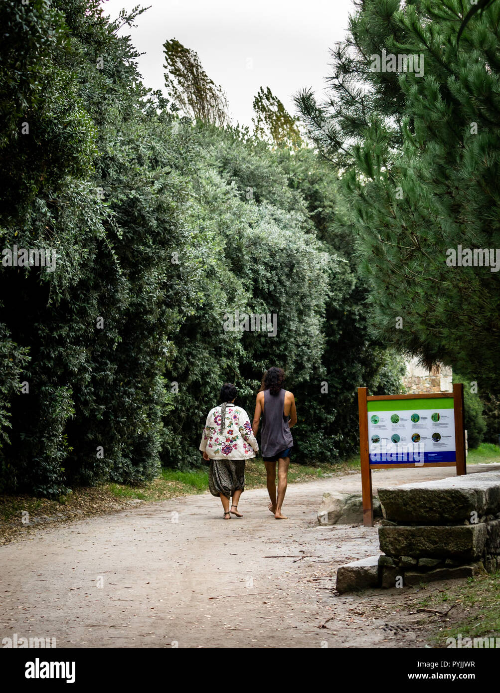 Vue arrière d'un couple hippie en passant devant un panneau dans un parc. Banque D'Images