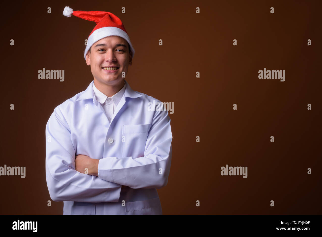 Beau jeune homme multi-ethnique médecin contre fond brun Banque D'Images