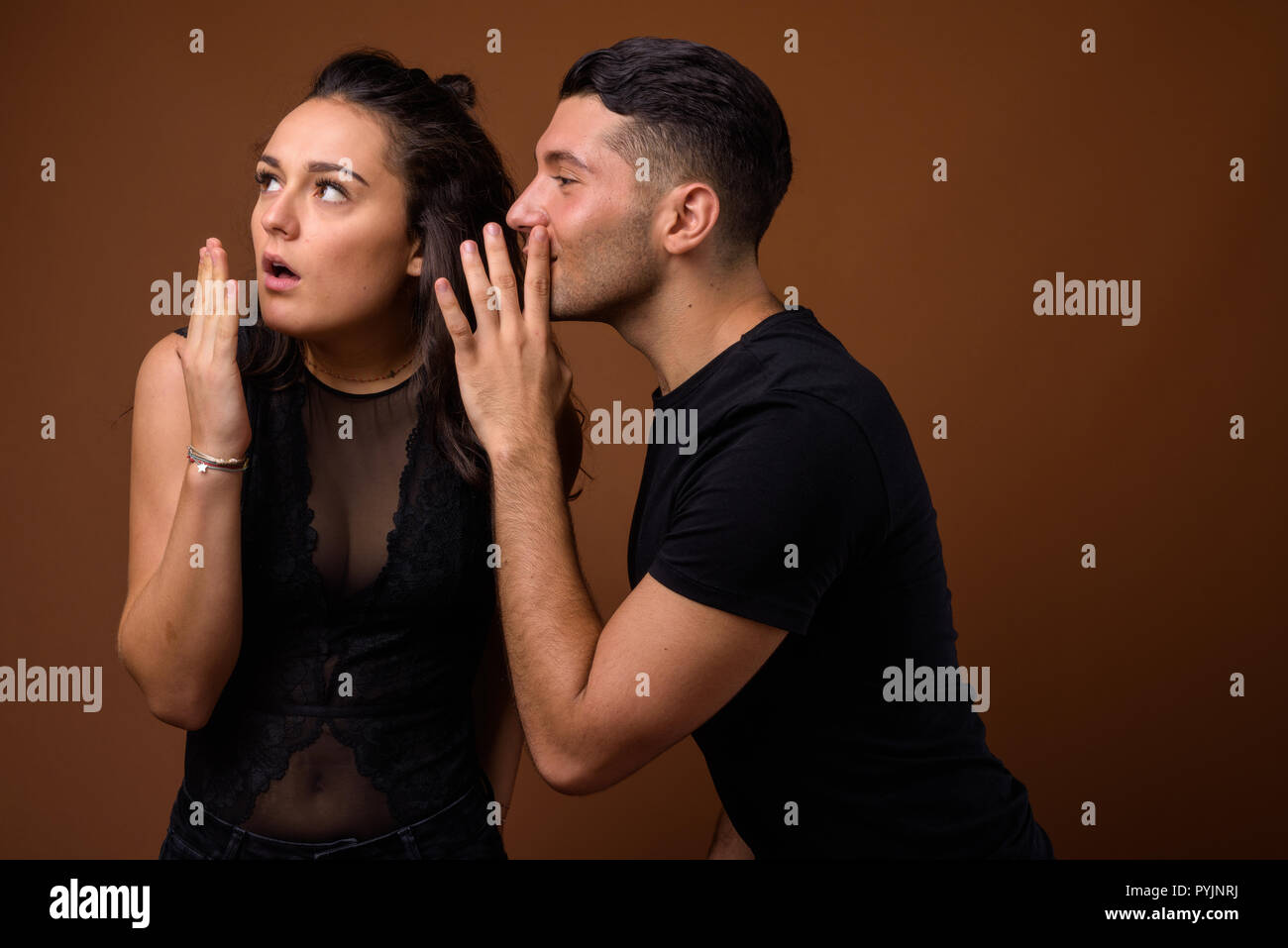 Jeune couple ensemble et dans l'amour contre fond brun Banque D'Images