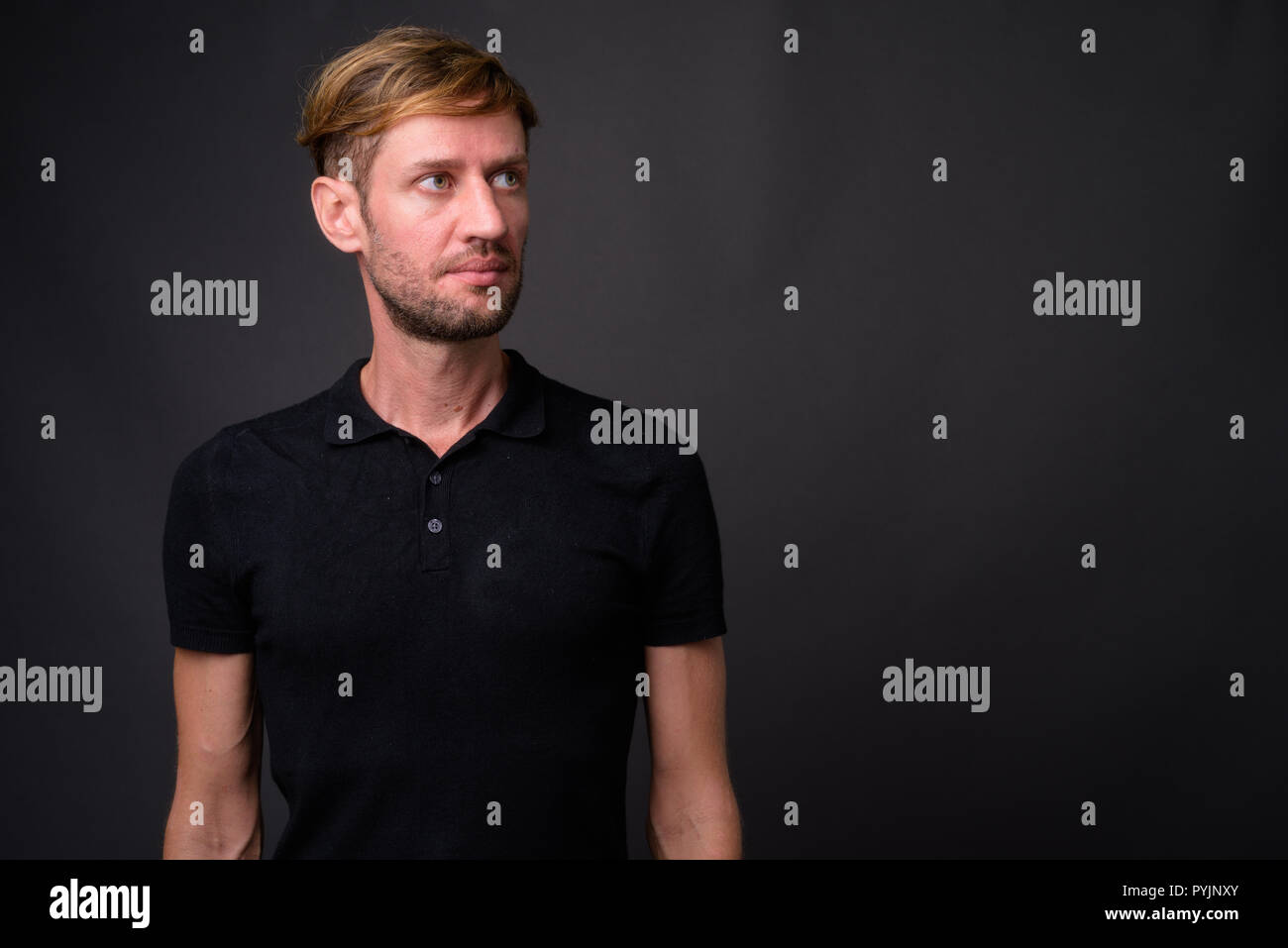 Portrait d'homme barbu blond contre l'arrière-plan gris Banque D'Images