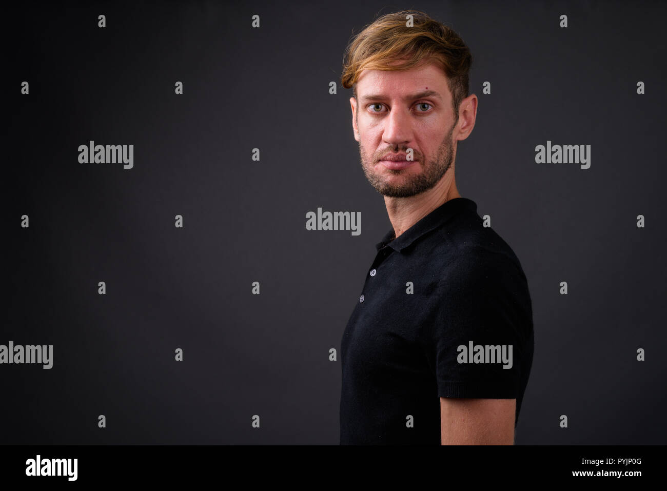 Portrait d'homme barbu blond contre l'arrière-plan gris Banque D'Images