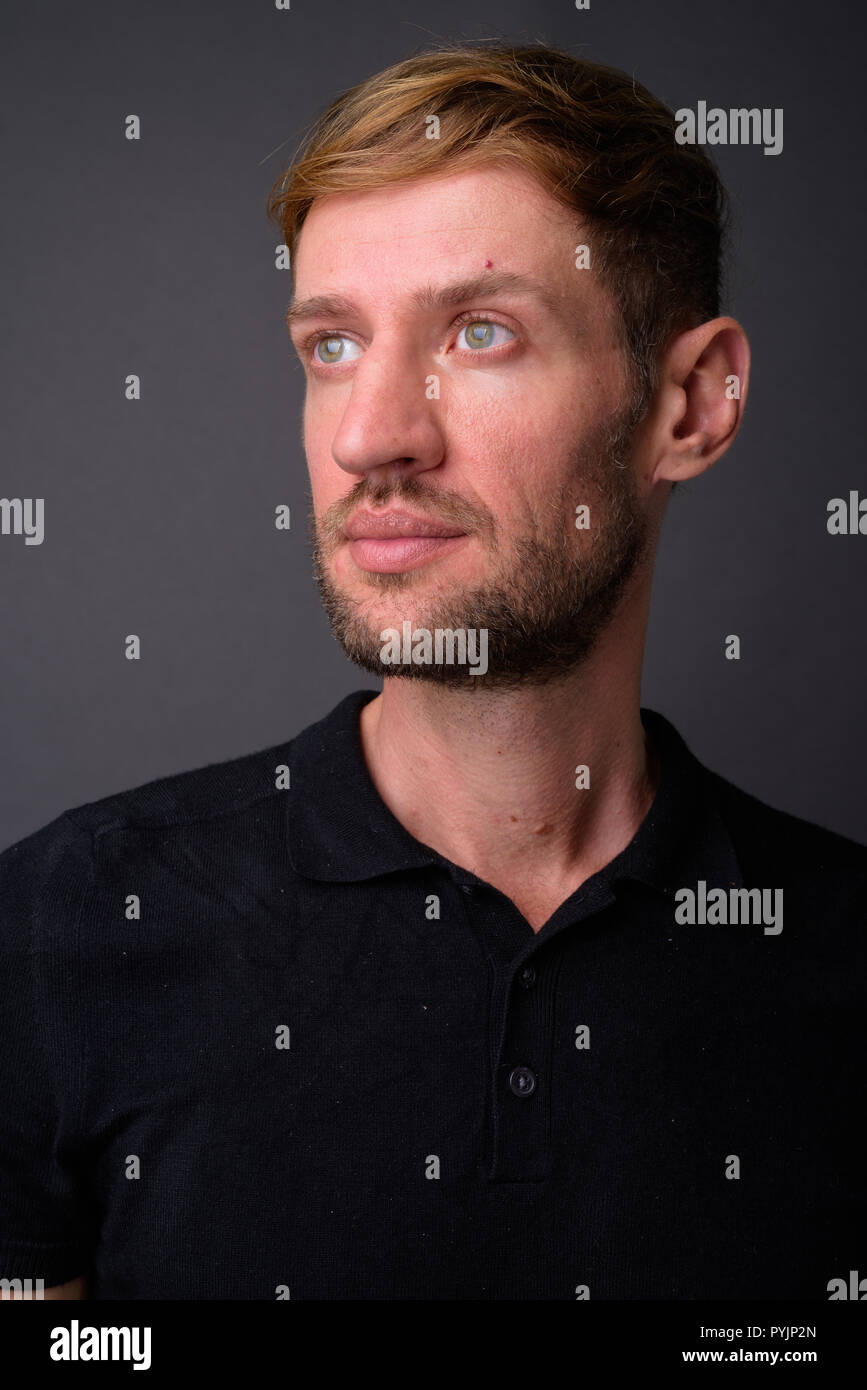 Portrait d'homme barbu blond contre l'arrière-plan gris Banque D'Images