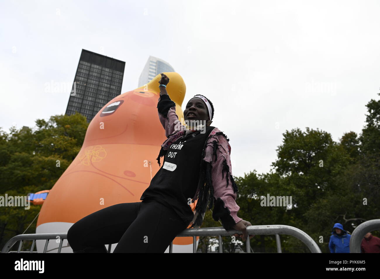 New York, États-Unis 28 octobre 2018. Statue de la liberté climber Patricia Okoumou en face d'un ballon de 20 cm de haut représentant le Président Trump comme un bébé en couches jetables pendant un rassemblement à Battery Park par des manifestants appelant à Trump destitution. Les manifestants ont utilisé des ballons semblables dans d'autres manifestations anti-Trump aux États-Unis et au Royaume-Uni Le rallye et mars a été organisée par un groupe appelé par le peuple qui accuse Trump d'avoir commis des crimes et délits majeurs. Okoumou, originaire du Congo, est traduit devant un tribunal fédéral de Manhattan le 17 Dec pour des accusations liées à son acte de désobéissance civile le 4 juillet Banque D'Images