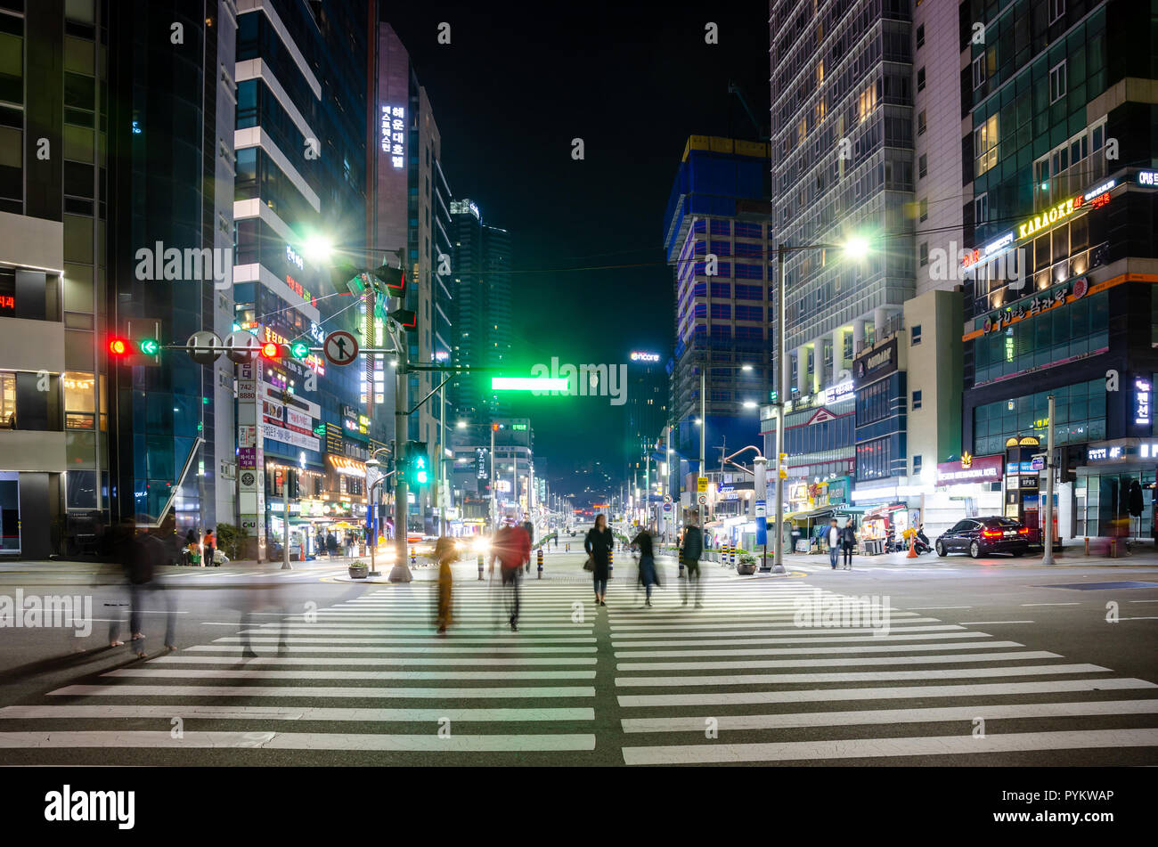 Les gens traversent un passage pour piétons dans la nuit à Haeundae, Busan, Corée du Sud. Derrière, la rue est pleine ou un éclairage brillant dans l'obscurité. Banque D'Images
