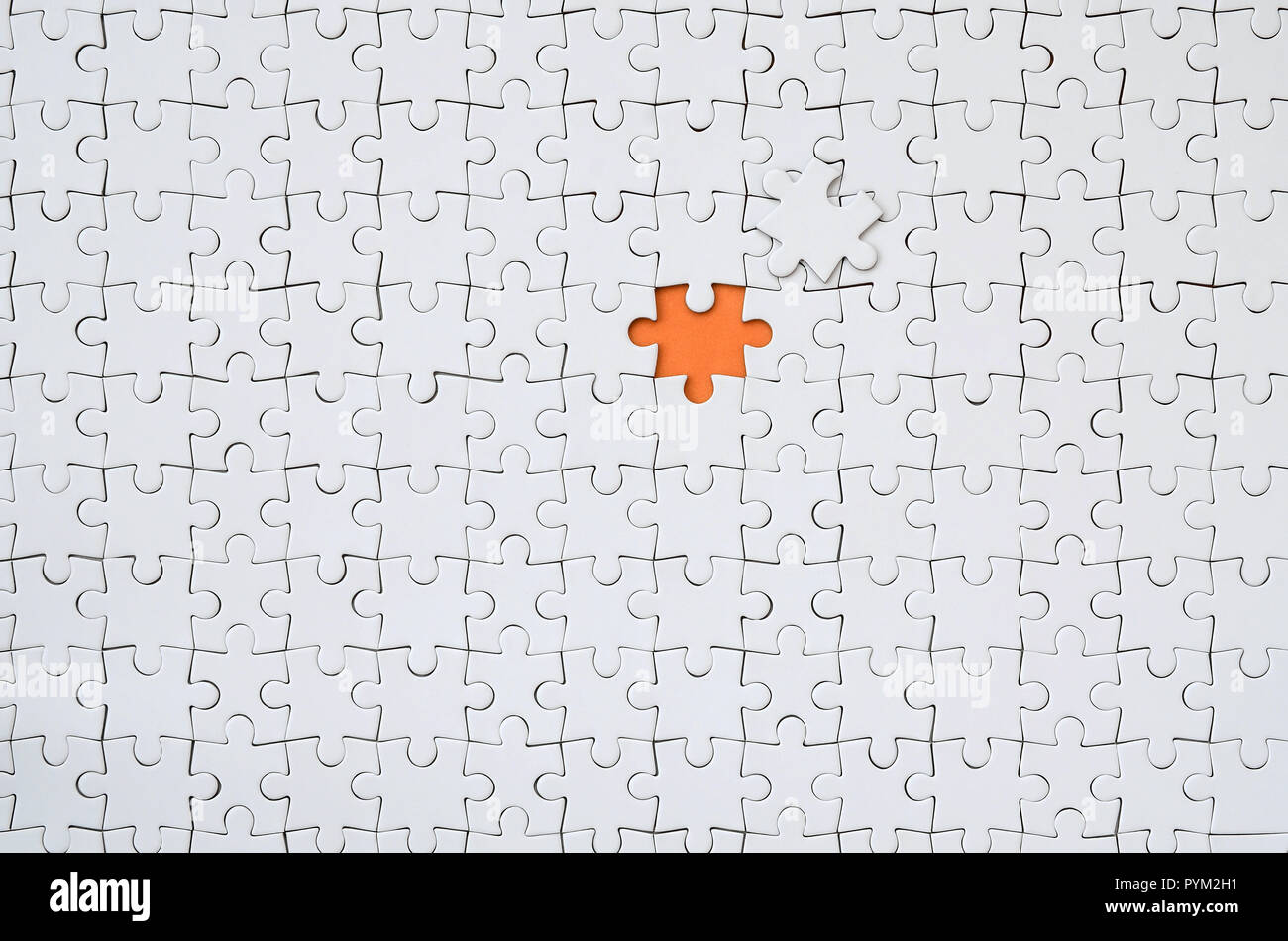 La texture d'un casse-tête blanche dans un état assemblé avec un élément  manquant formant un espace orange Photo Stock - Alamy