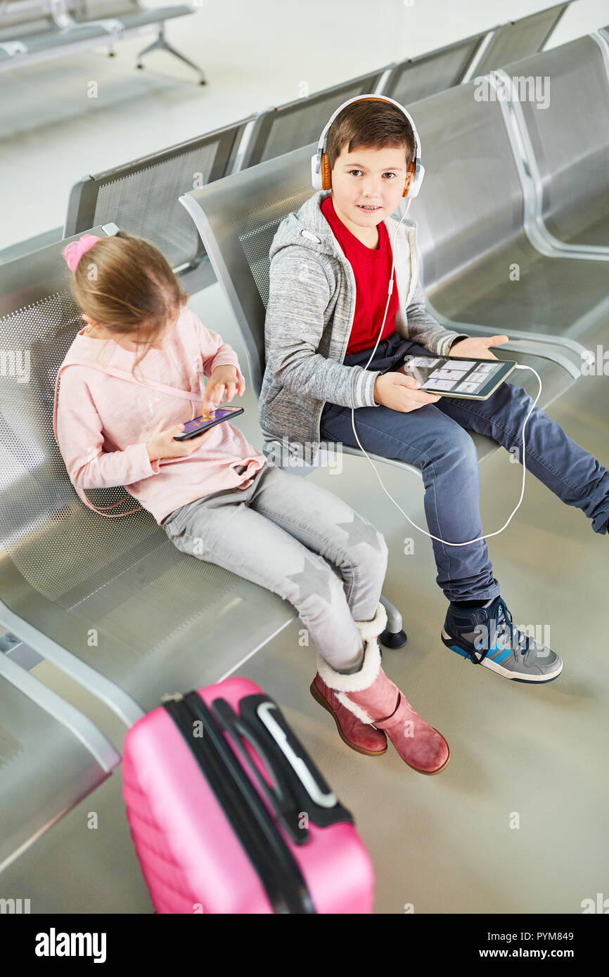 Les enfants sur le trajet jouer avec tablet PC dans les médias sociaux et avec le smartphone Banque D'Images