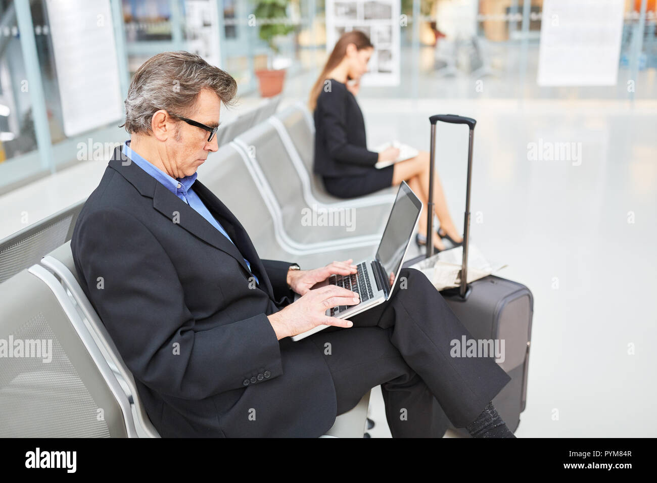 Manager écrit sur l'ordinateur portable dans le terminal de l'aéroport avant son voyage d'affaires Banque D'Images