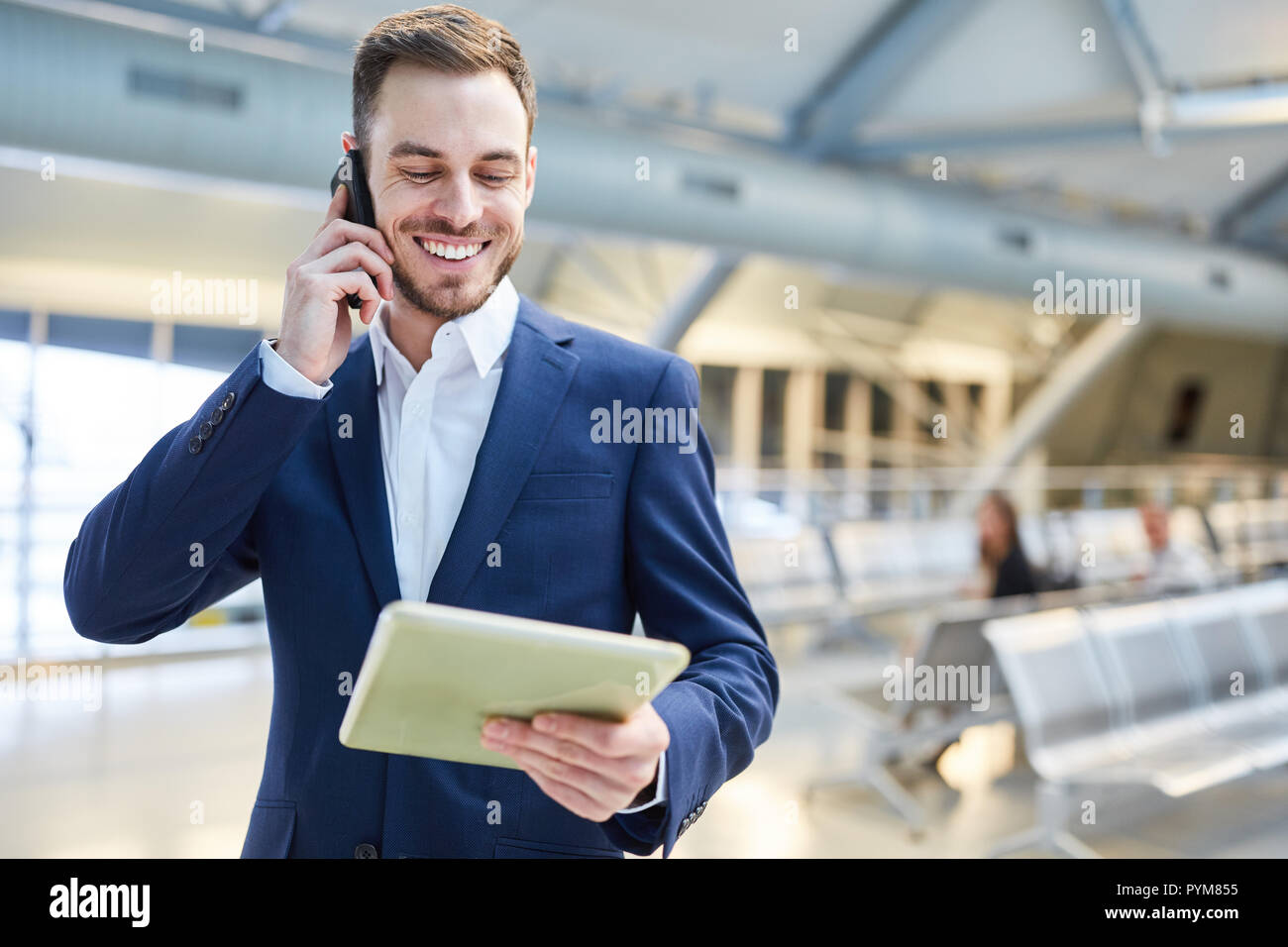 Businessman with tablet pc et téléphone mobile est heureux à propos de bonnes nouvelles dans la borne Airport Banque D'Images