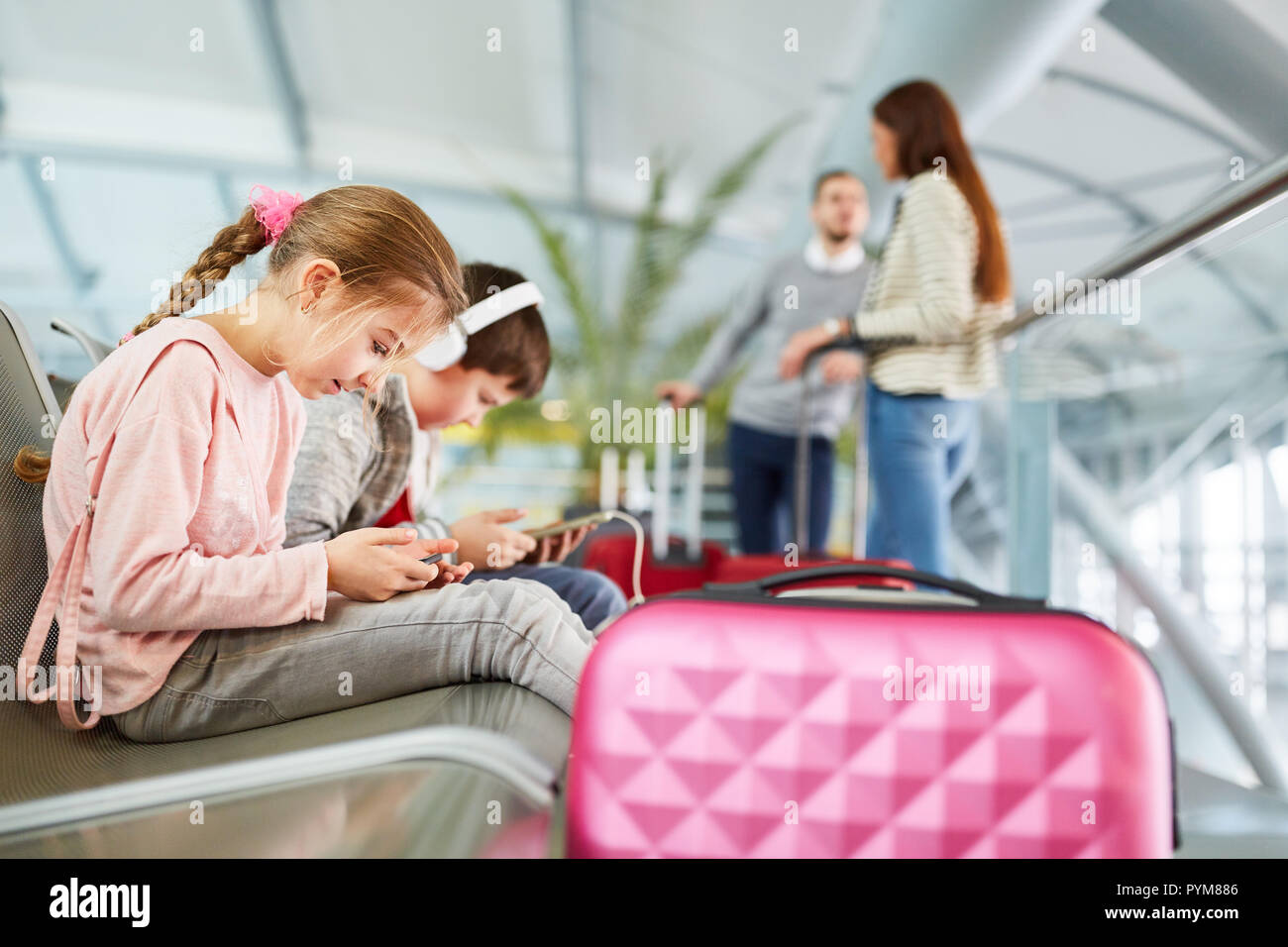 Les enfants jouent avec tablette et smartphone dans le temps d'attente avant le vol à l'aéroport Banque D'Images