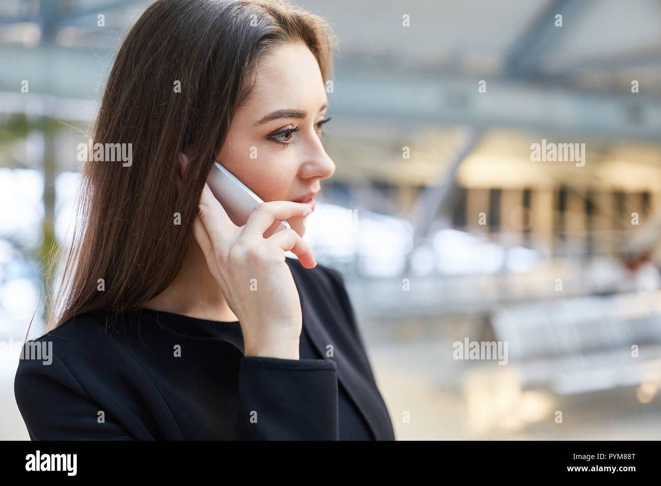 Femme d'affaires fait un appel au terminal de l'aéroport avant de partir pour son voyage d'affaires Banque D'Images