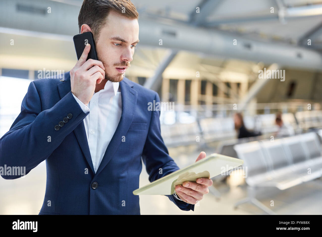 Business man using mobile phone in airport terminal est effrayée à l'idée d'un message Banque D'Images