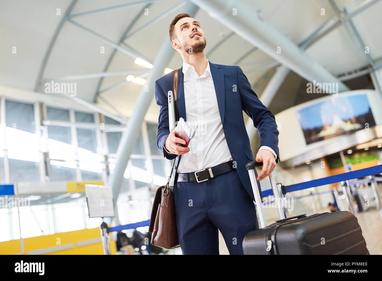 L'homme d'affaires dans le terminal de l'aéroport ressemble à l'escale pour le vol de correspondance Banque D'Images