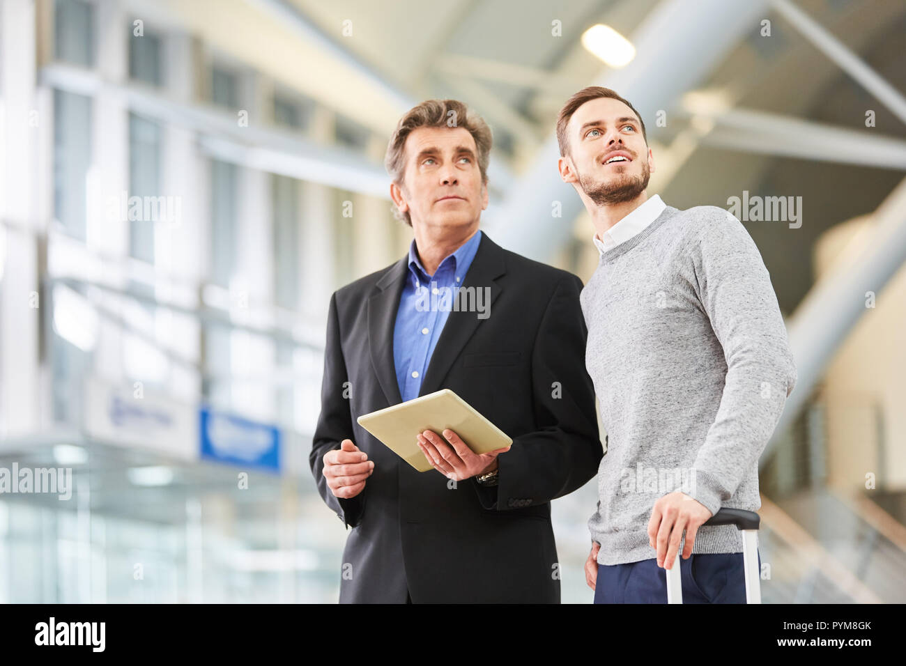 Deux hommes d'affaires au terminal de l'aéroport avec l'ordinateur tablette avant un voyage d'affaires Banque D'Images