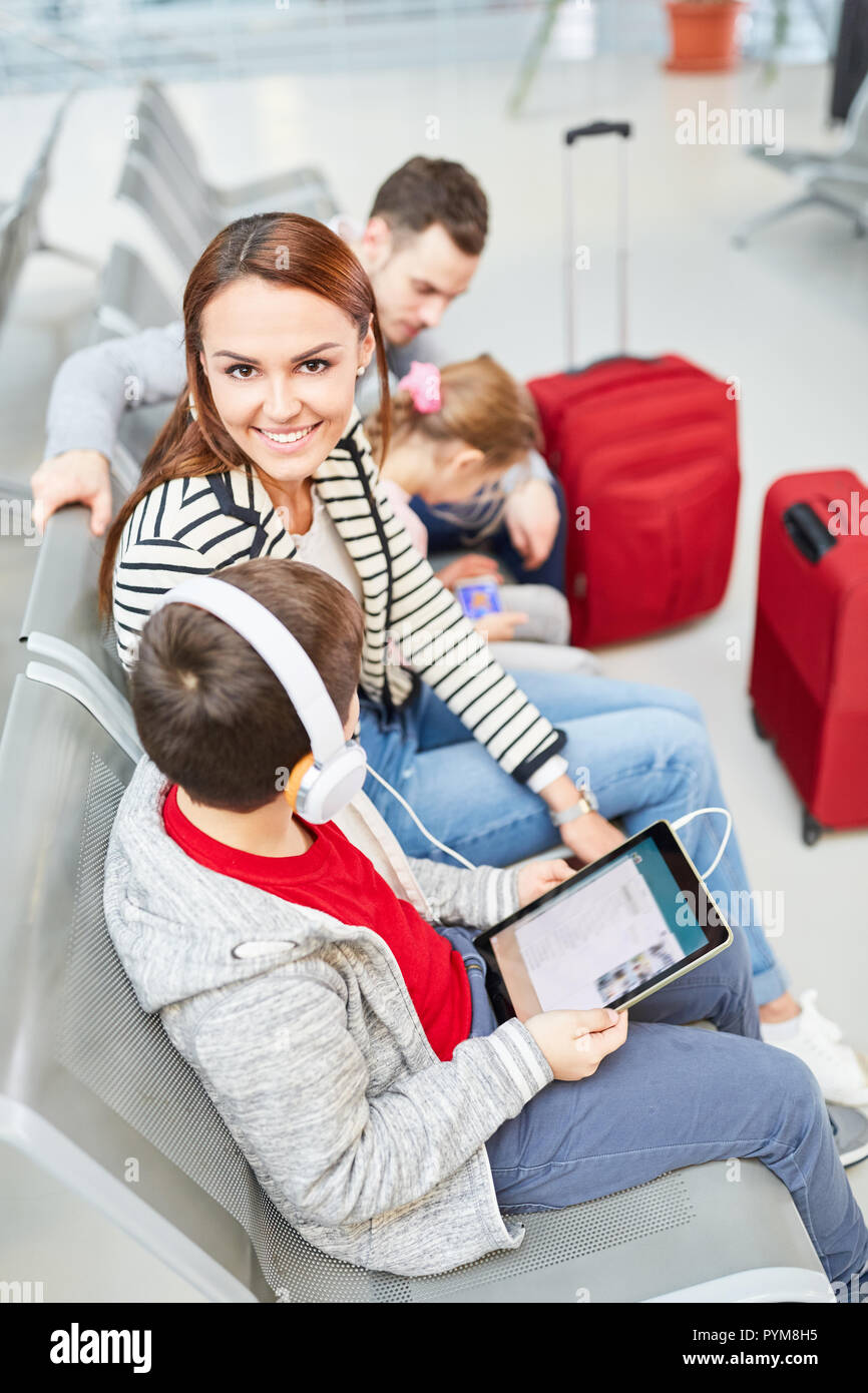 Garçon écoute de la musique avec casque en zone d'attente de l'aéroport avec sa famille Banque D'Images