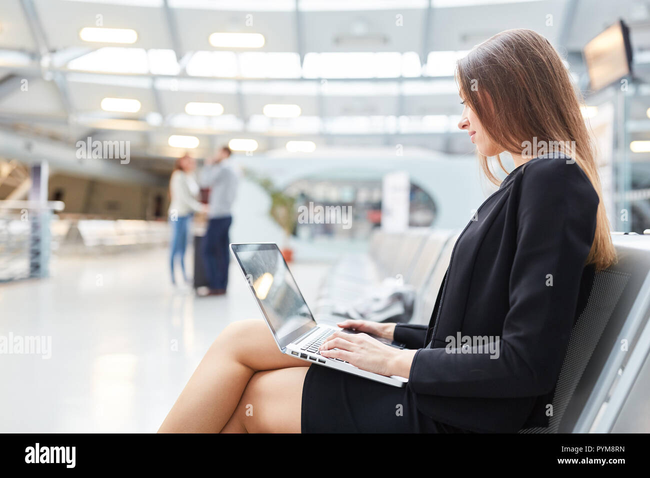 Young business woman with laptop computer in airport terminal avant un voyage d'affaires Banque D'Images