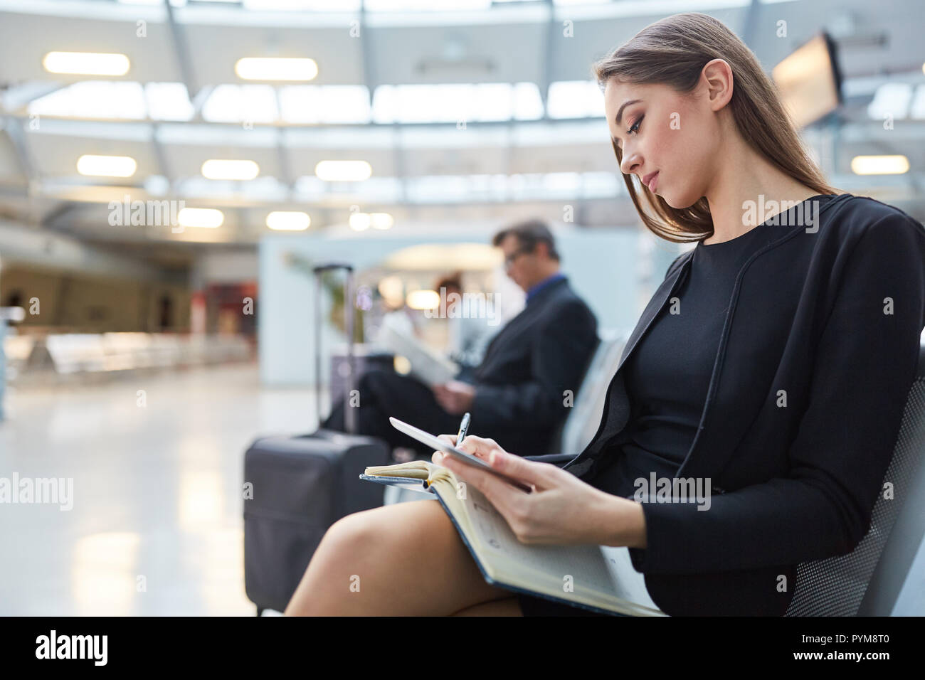 En femme d'attente dans l'aéroport avec ses plans carnet de rendez-vous d'affaires Banque D'Images