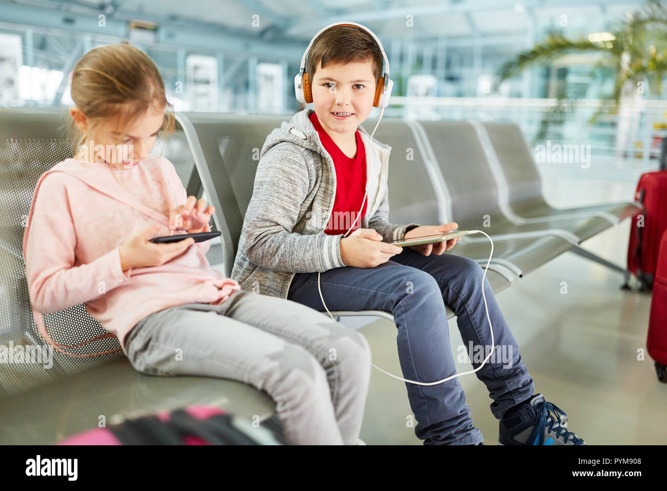 Frères et sœurs Les enfants jouent avec tablet et smartphone et s'amuser dans le terminal de l'aéroport Banque D'Images