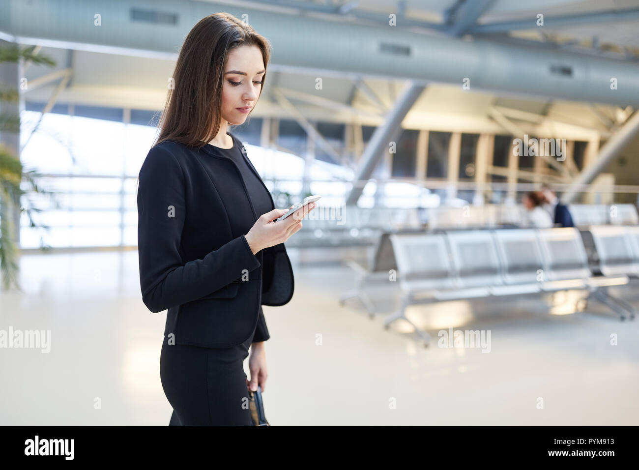 Jeune femme en voyage d'affaires lit un message texte sur le smartphone dans l'aéroport Banque D'Images