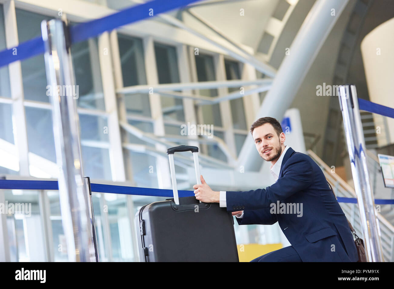 Jeune homme d'affaires en voyage d'affaires avec chariot en attente dans la borne Airport Banque D'Images