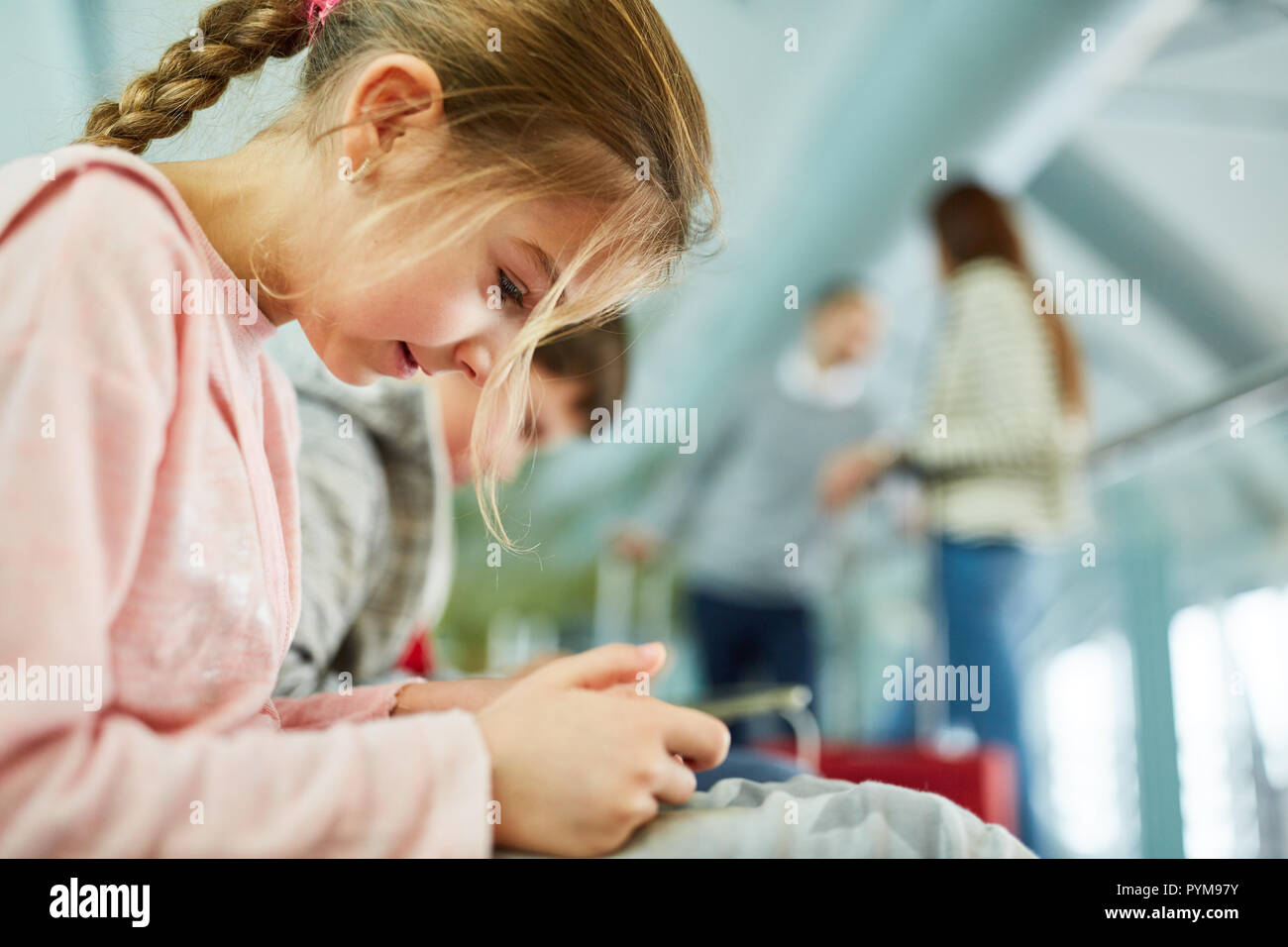 Girl in airport terminal avec le smartphone vend attendre dans les médias sociaux Banque D'Images