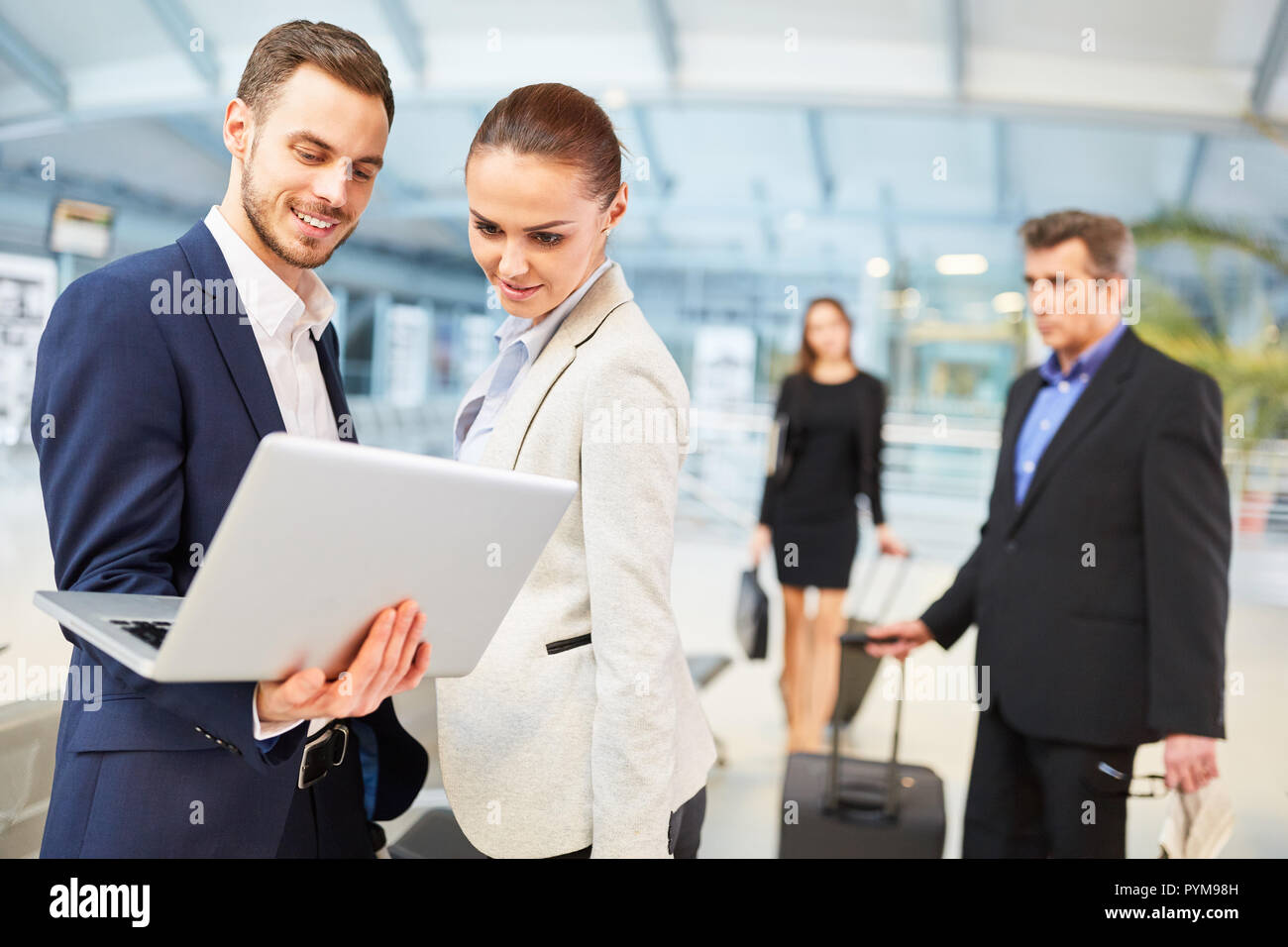 Les gens d'affaires de l'aéroport avec un ordinateur portable la lecture des nouvelles avant leur voyage d'affaires Banque D'Images
