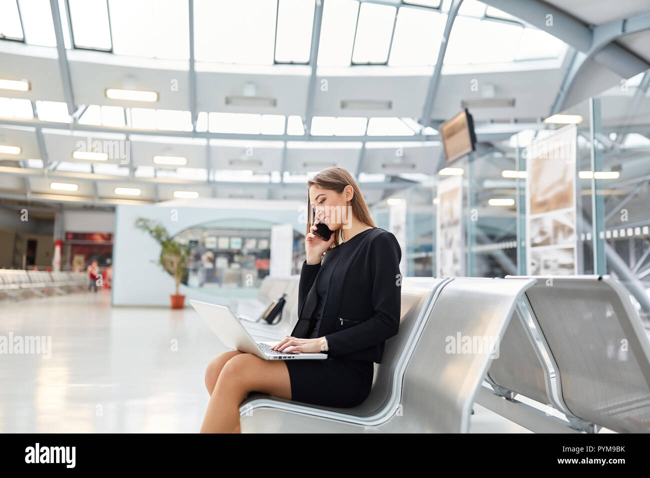 Young businesswoman is phoning avec smartphone en terminal de l'aéroport avant un voyage d'affaires Banque D'Images