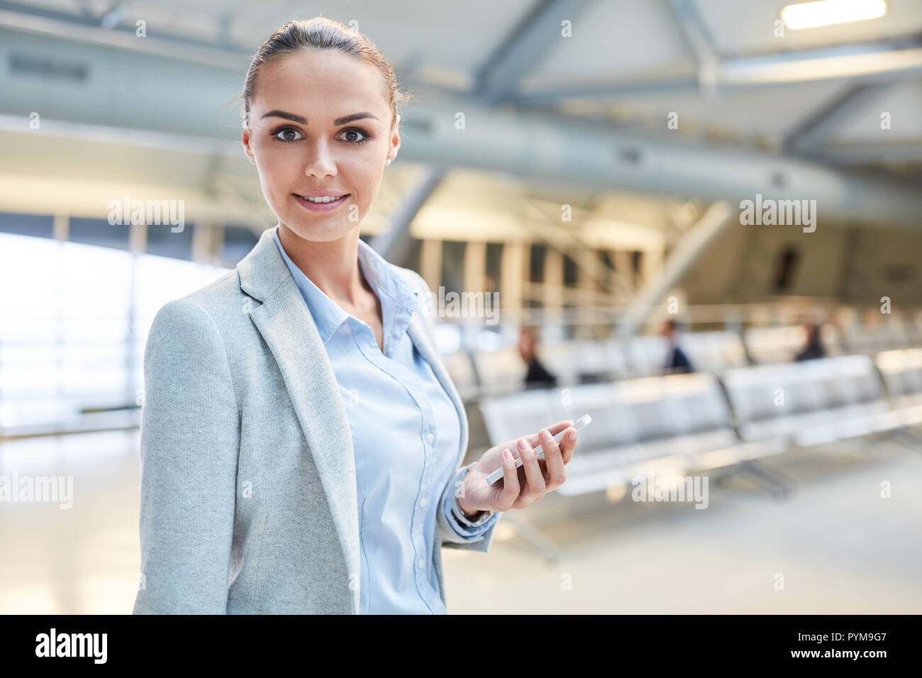 Jeune femme d'affaires réussie à l'aide du smartphone sur le voyage d'affaires à airport terminal Banque D'Images