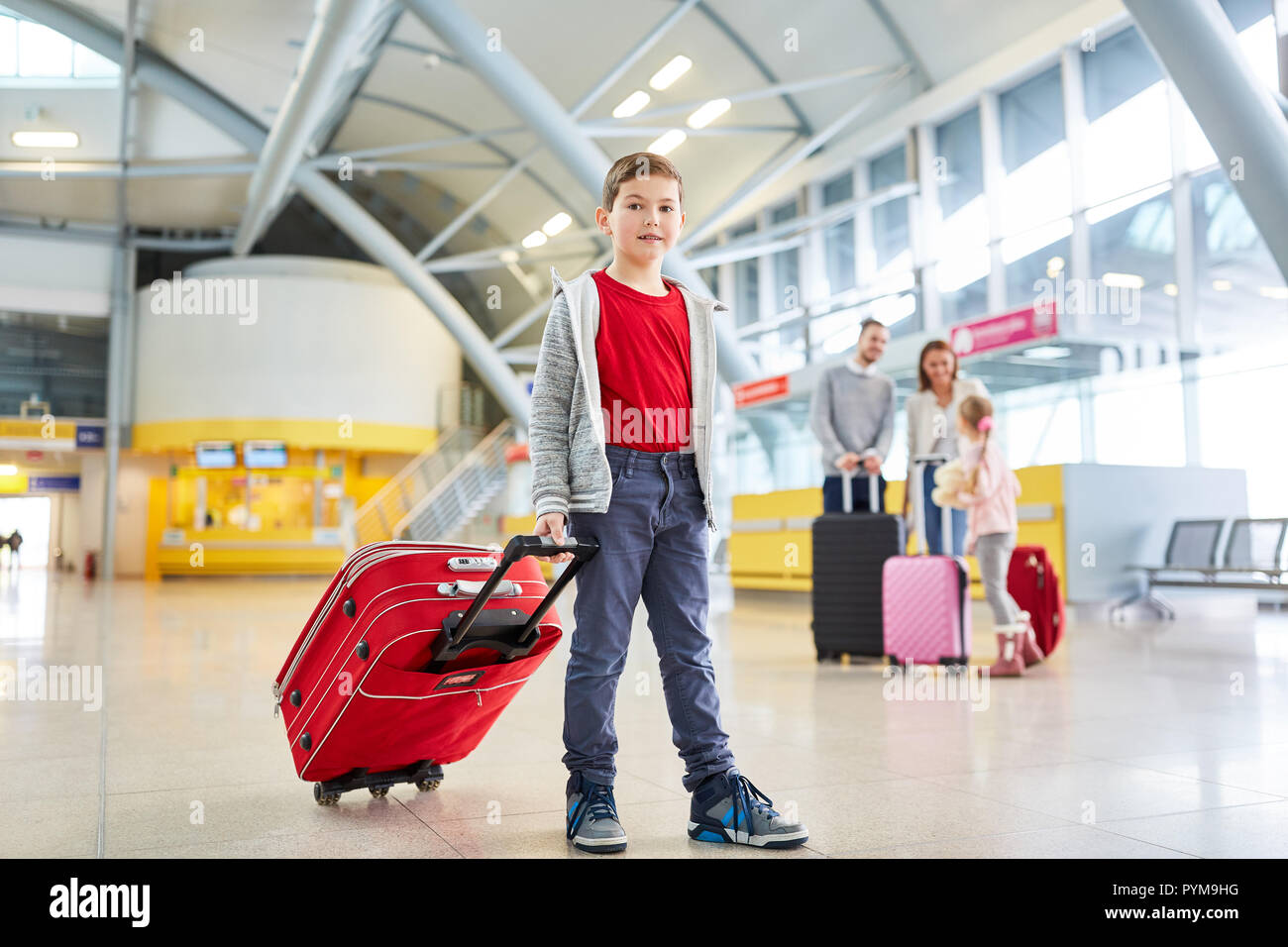 Garçon avec chariot de terminal de l'aéroport avec ses parents et sa sœur  dans l'arrière-plan Photo Stock - Alamy