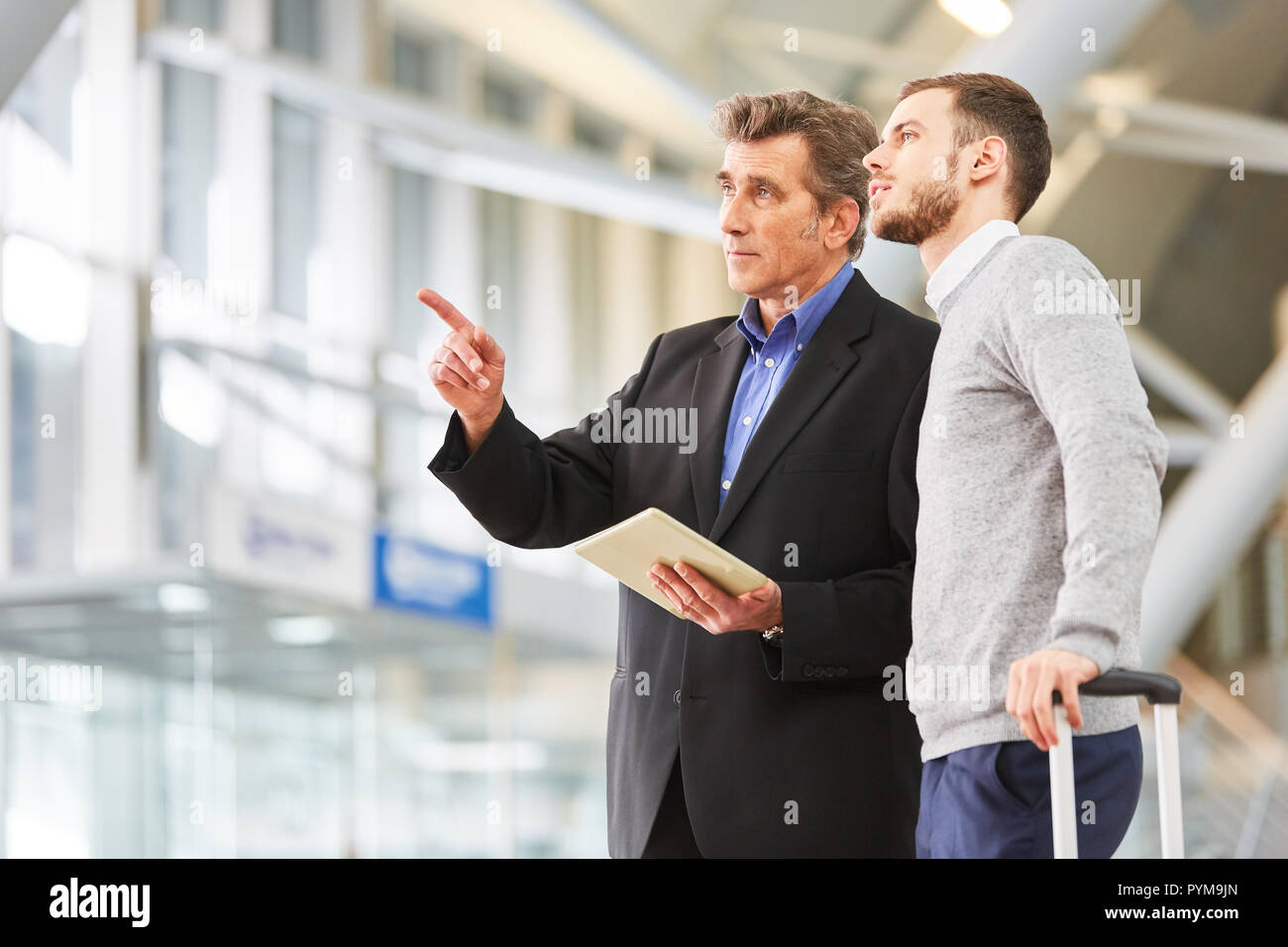 Deux gestionnaires avec les tablettes électroniques à l'aéroport de discuter leur voyage d'affaires Banque D'Images