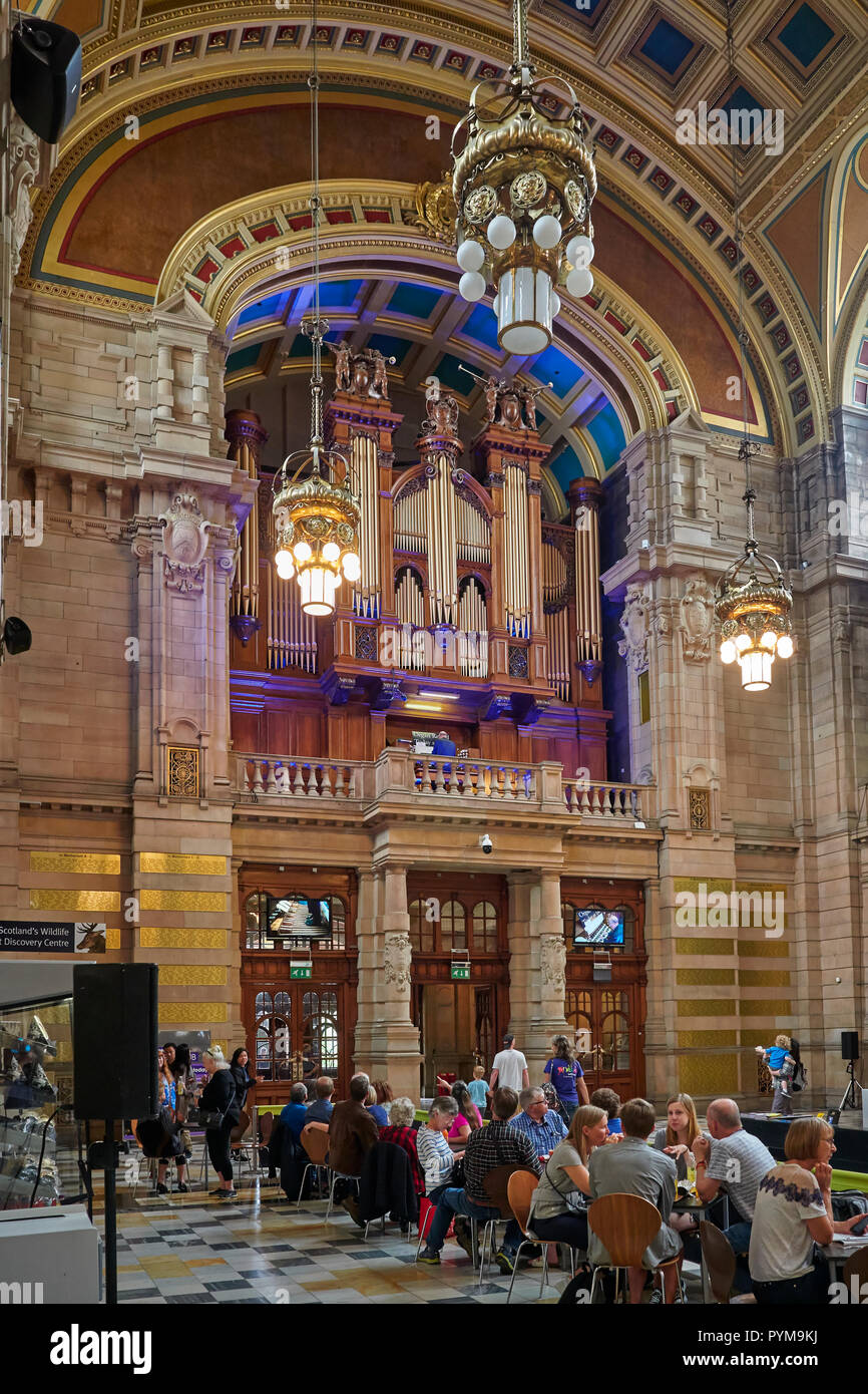 Les gens assis à des tables et des chaises à l'intérieur de l'entrée du musée de Kelvingrove et écouter un récital d'orgue. Glasgow, Ecosse, Royaume-Uni. Banque D'Images