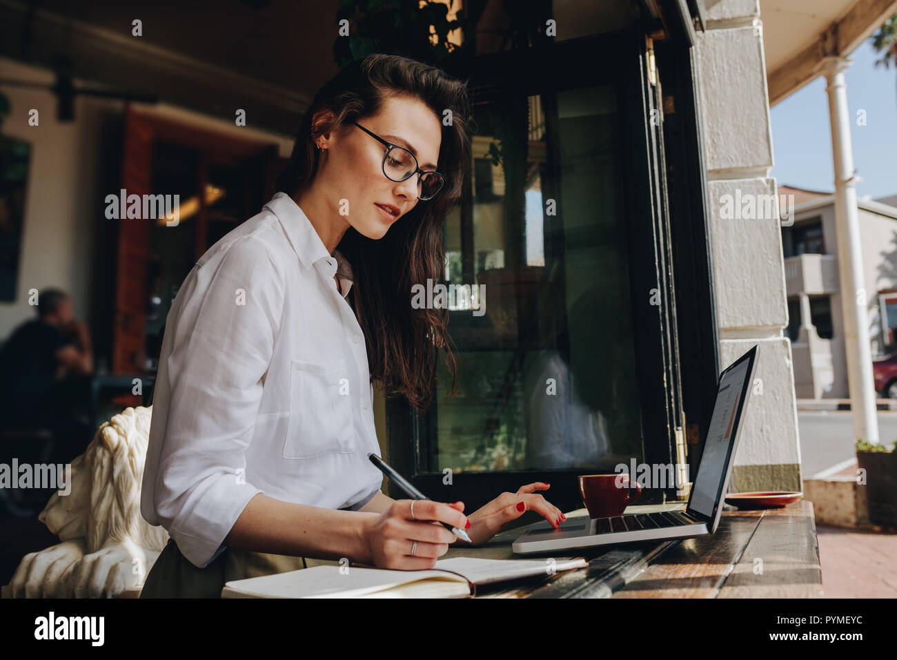 femme d'affaires au café travaillant sur ordinateur portable et prenant des notes. Femme professionnelle travaillant dans un café. Banque D'Images
