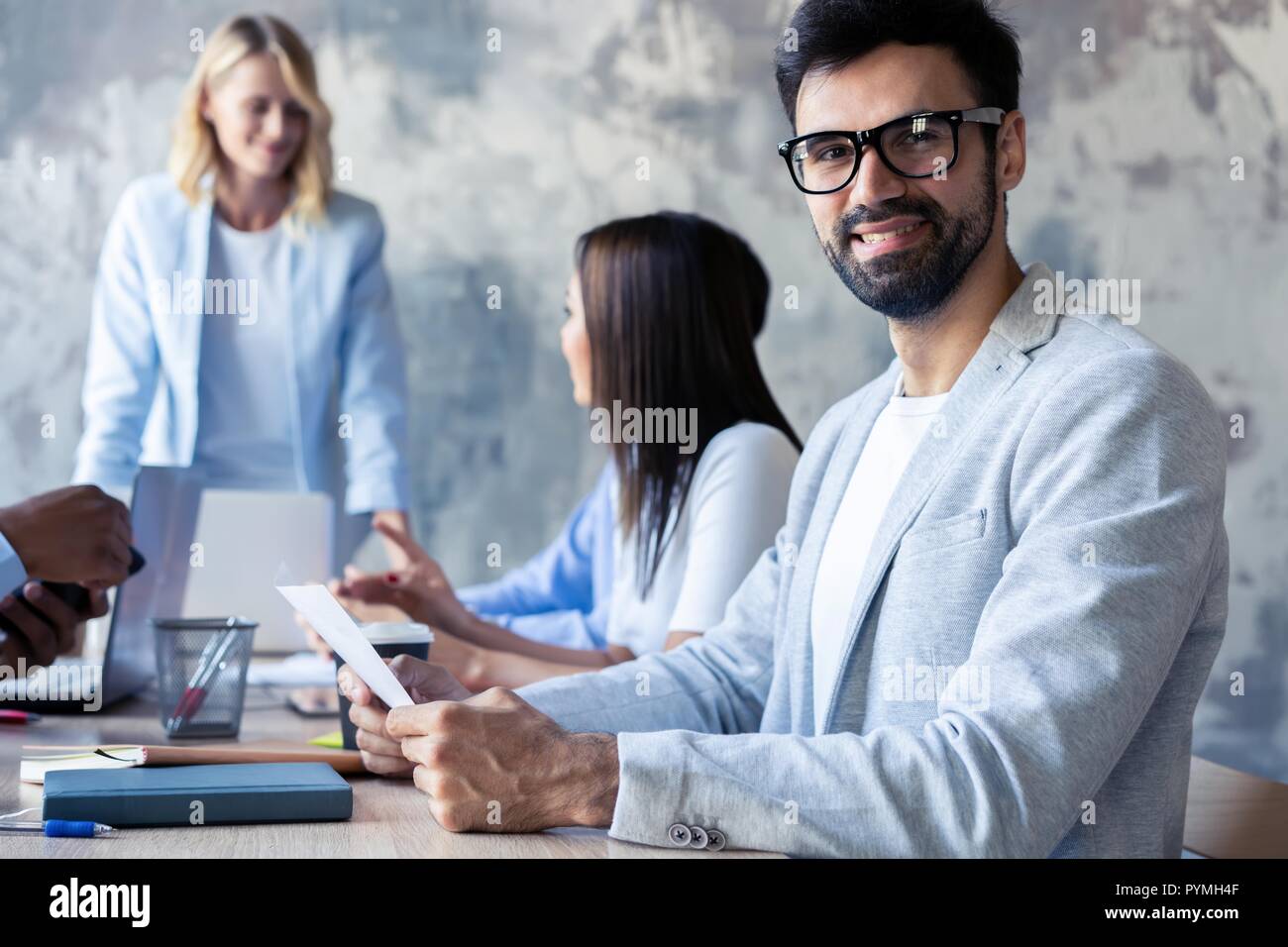 Heureux l'homme d'affaires à puce avec l'équipe de discuter à l'arrière-plan. Banque D'Images