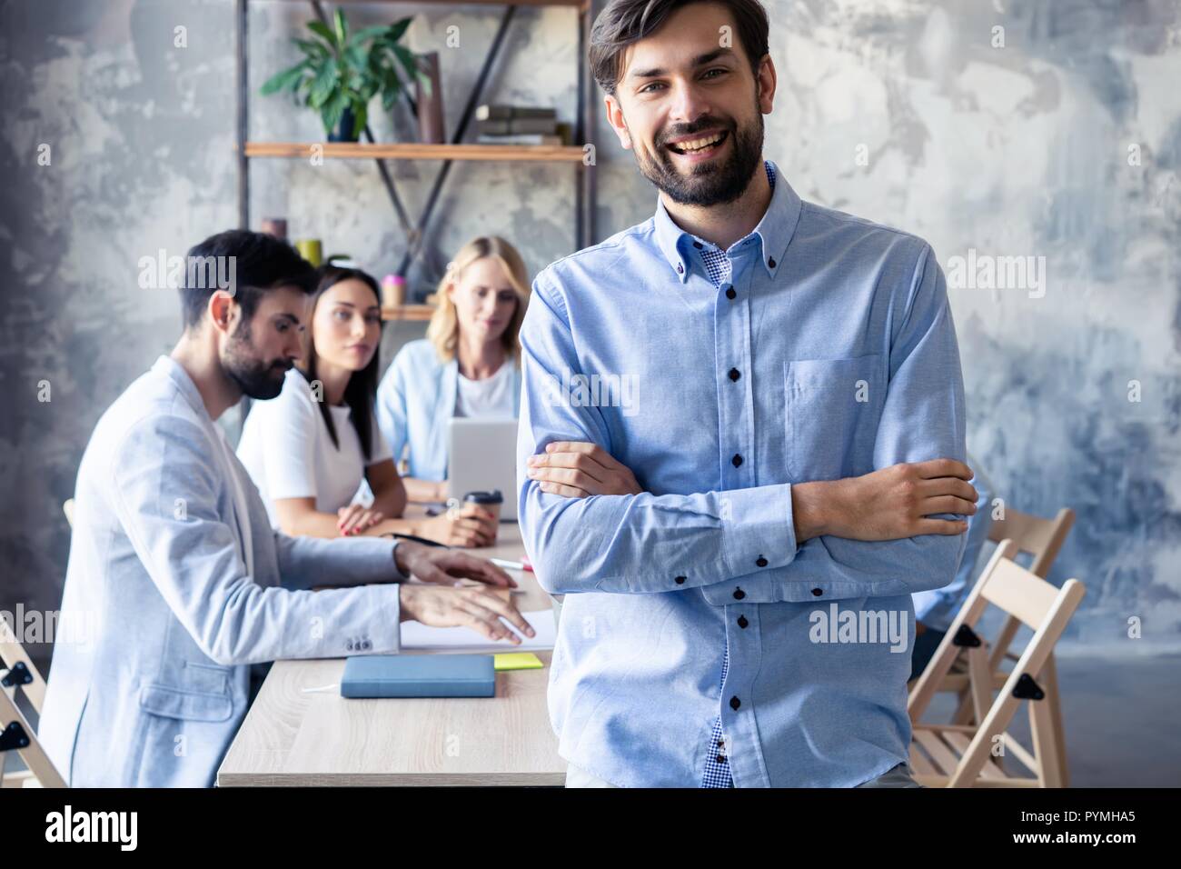 Heureux l'homme d'affaires à puce avec l'équipe de discuter à l'arrière-plan. Banque D'Images