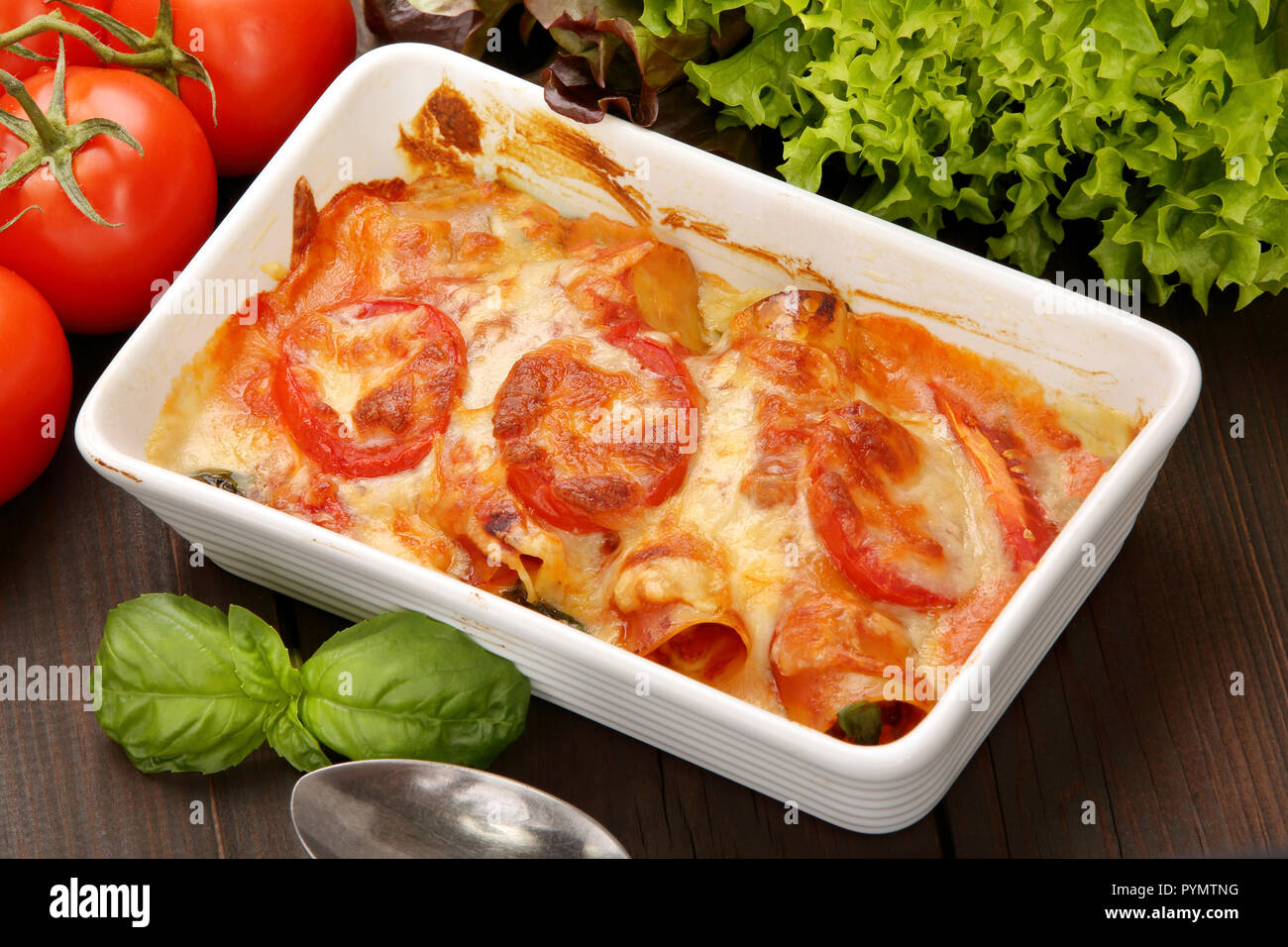 Caneloni farcies de viande et de fromage fondu dans un bol blanc sur fond de bois grunge Banque D'Images